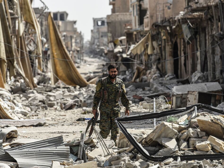 A member of the Syrian Democratic Forces, a group allied with the United States, walks through debris in Raqqa, Syria, formerly the de facto capital of Islamic State. (Bulent Kilic/AFP/Getty Images)
