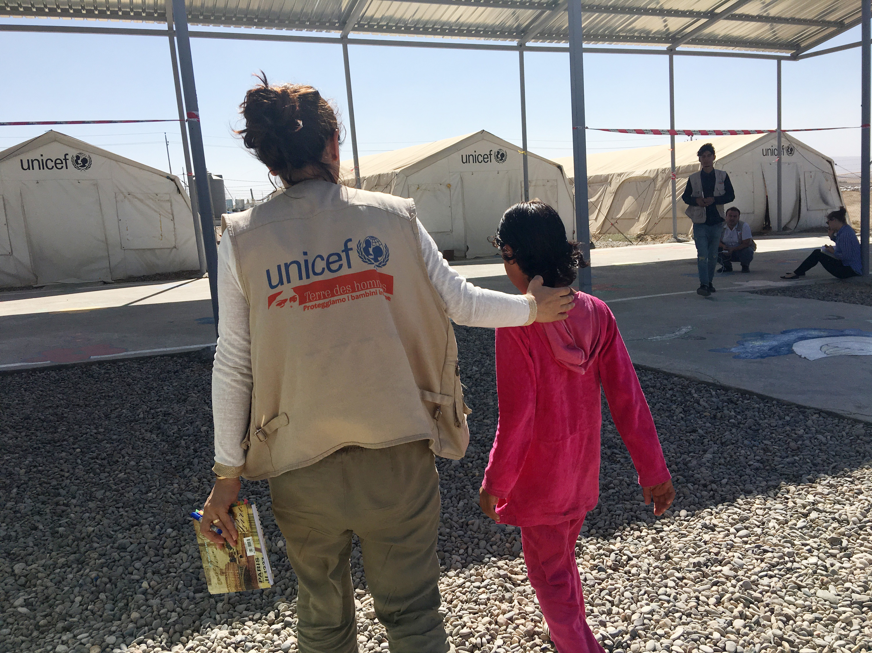 Kawkab walks with a social worker in the Dabaga camp for displaced Iraqis. Kawkab says she was seven or eight when she saw ISIS militants shoot her mother dead. &quot;They shot her with an assault rifle,&quot; she says. &quot;They shot her and she died and they threw her off the bridge. I asked them, 'Why did you kill her? She's my mother. She didn't do anything.'&quot; (NPR)