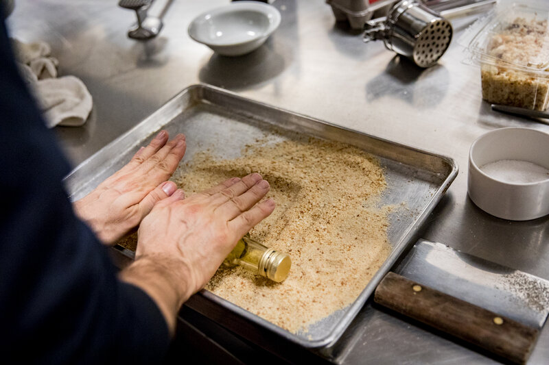 NPR's food processor wasn't producing a fine enough texture for Bottura, so he decided to manually crush the crumbs by rolling over them with a glass bottle from the kitchen. (Beck Harlan/NPR)