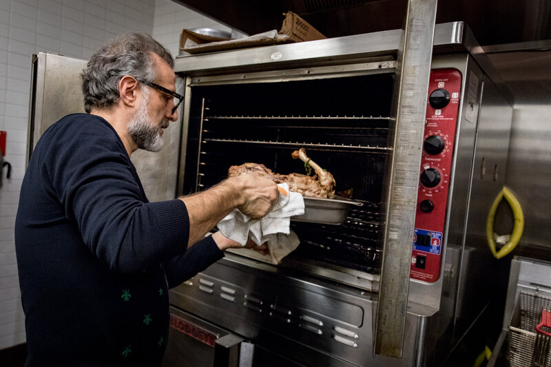 Bottura puts a turkey carcass, nestled on a baking sheet with veggie scraps, in the oven to roast and unlock its flavor. After about 45 minutes, the bones go in water to boil to become the broth for passatelli. (Beck Harlan/NPR)