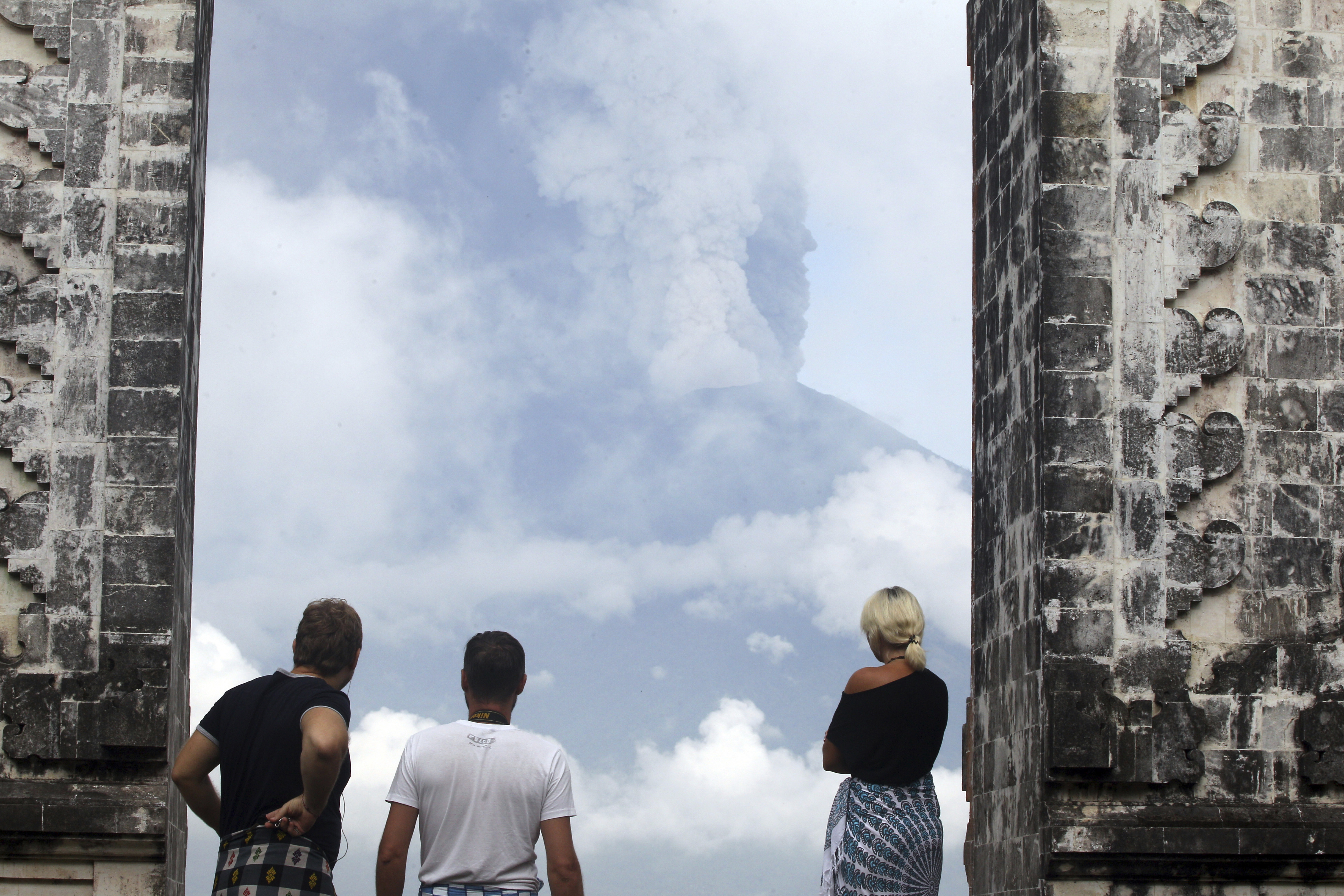 Tourists watch the Mount Agung volcano erupting as they visit a temple in Karangasem, Indonesia, on Monday.