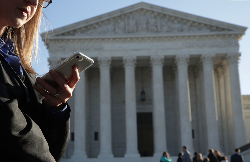 A woman checks her cellphone as she waits in line to enter the Supreme Court on Wednesday to hear arguments in <em>Carpenter v. United States </em>about the government's access to cellphone data. (Alex Wong/Getty Images)