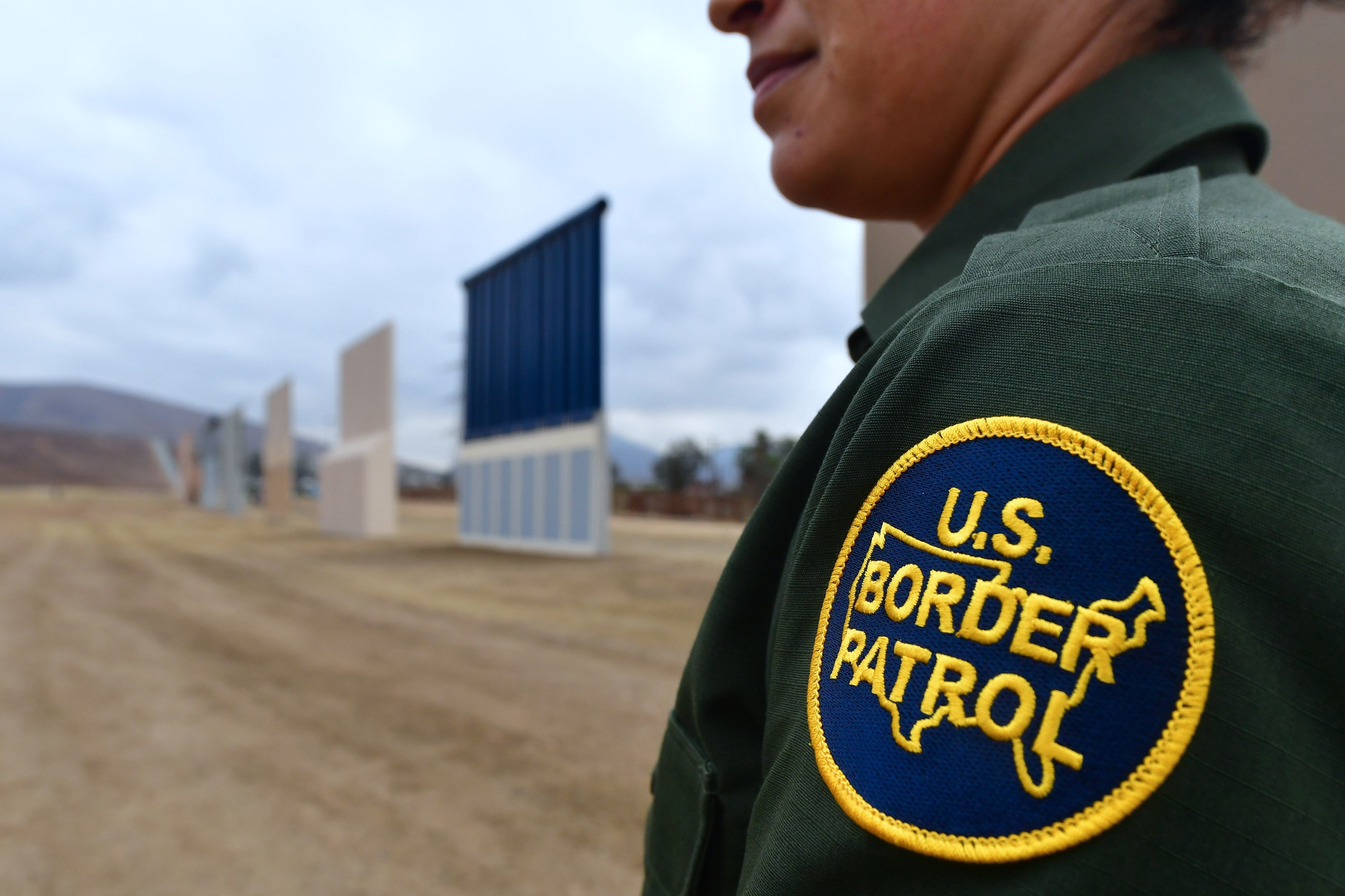 A U.S. Border Patrol officer stands near prototypes of President Trump's proposed border wall in San Diego. Border officers apprehended 310,531 people for being in the country illegally in fiscal 2017, a 25 percent decrease from the year before.