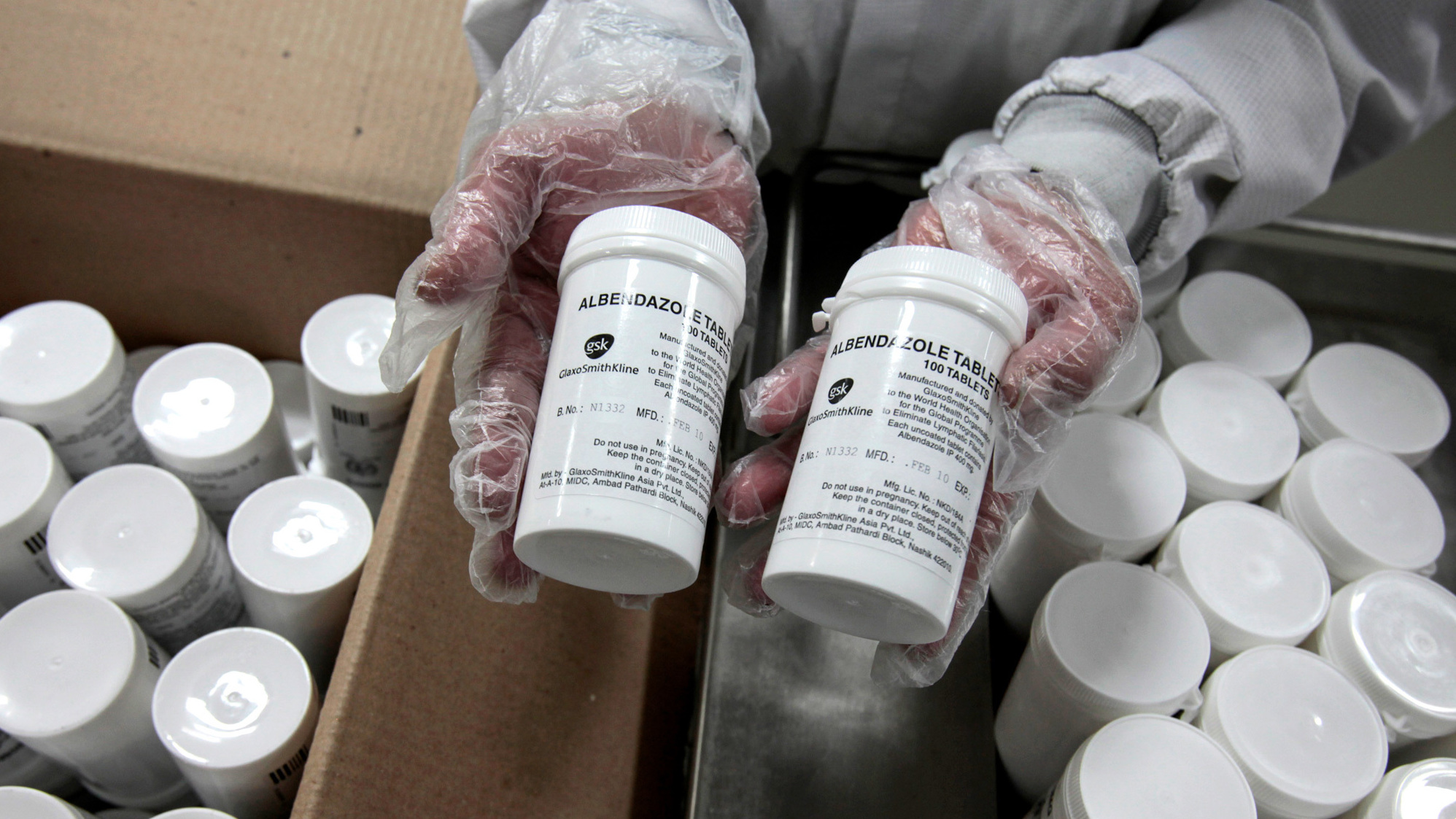 An employee of GlaxoSmithKline Pharmaceuticals holds bottles of albendazole, an anti-hookworm medication. (Bloomberg via Getty Images)