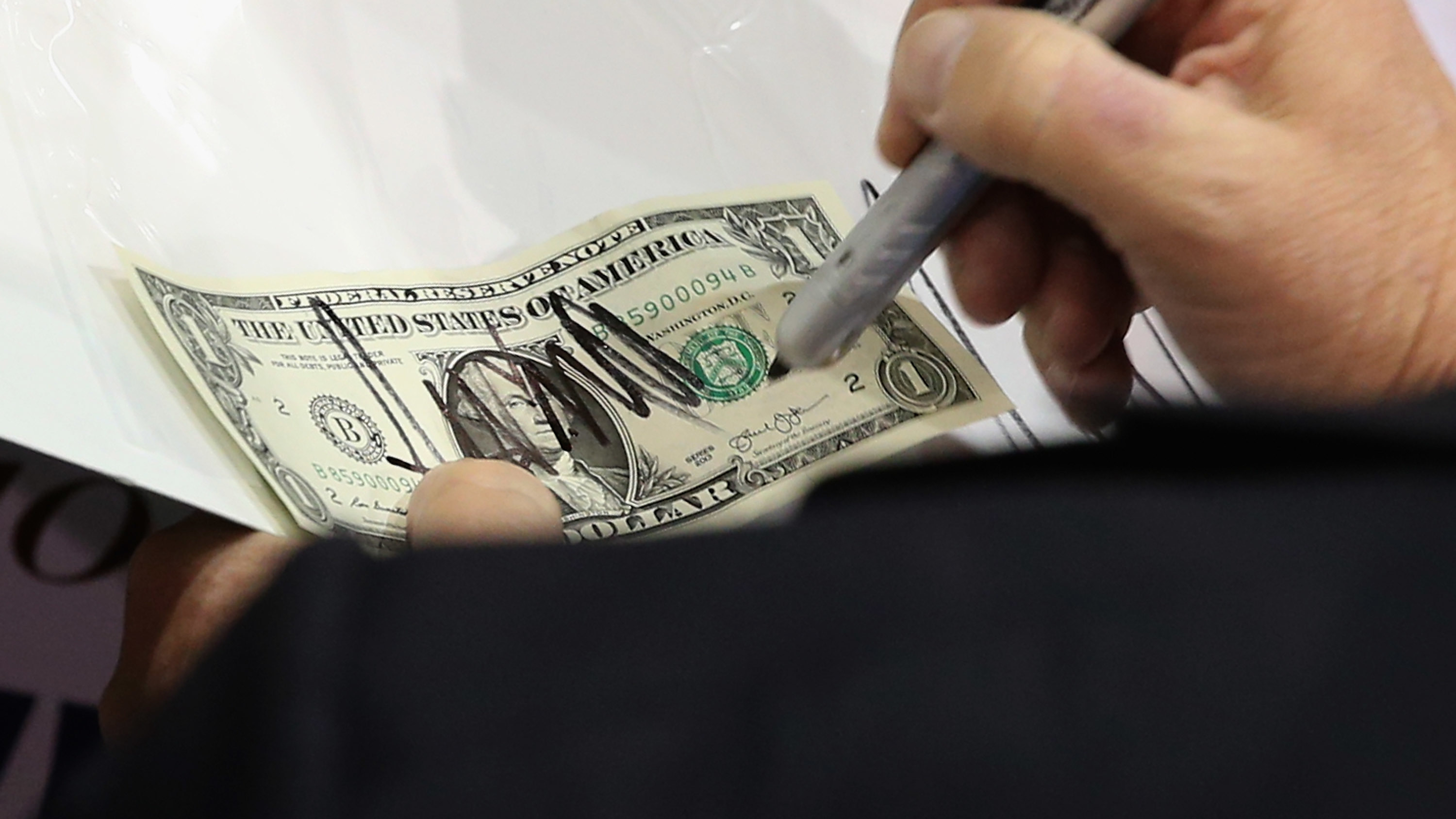 Donald Trump signs a dollar bill for a supporter during a campaign rally in Richmond, Va., during the presidential campaign. (Getty Images)