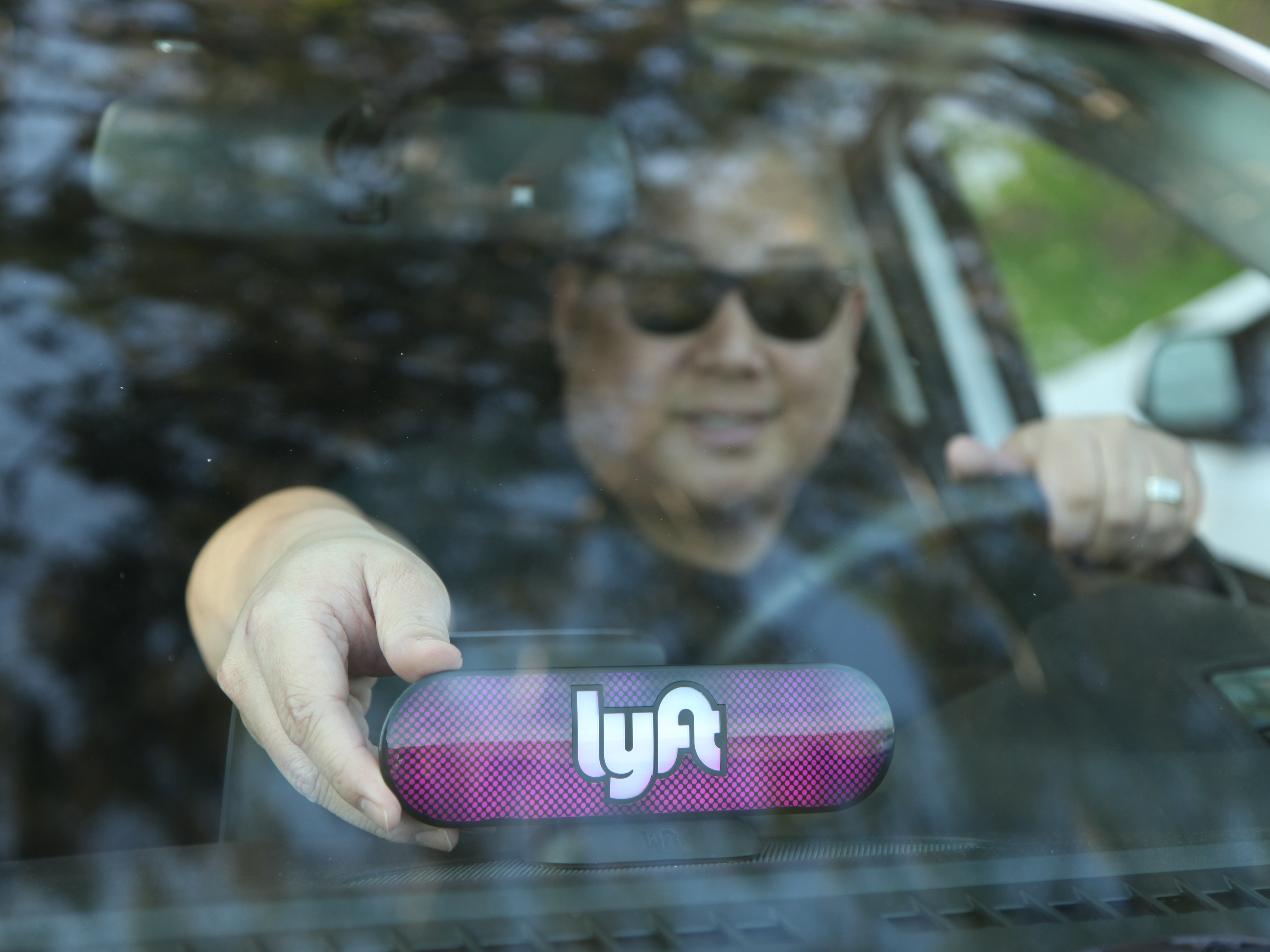 A Lyft driver places a company emblem on his dashboard Jan. 31, in San Francisco. Lyft announced it's offering education benefits, a move aimed at recruiting and retaining drivers in its competition with Uber. (Getty Images for Lyft)