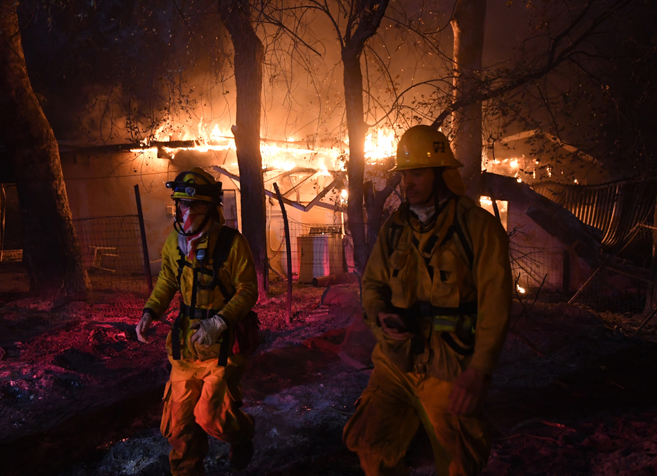 Firefighters step back from a burning house in Carpinteria, Calif., after discovering downed live power lines nearby on Sunday. (Mark Ralston/AFP/Getty Images)