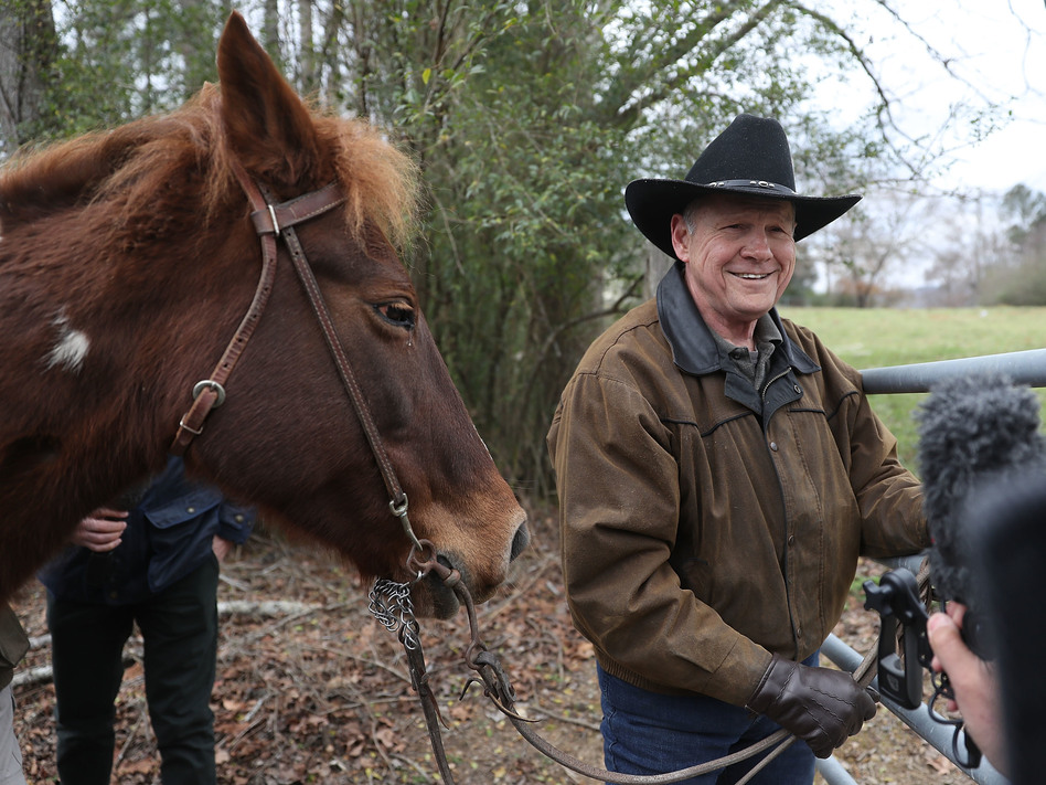 Republican Senate candidate Roy Moore rides in on a horse to vote and is pictured preparing to tie it up. (Joe Raedle/Getty Images)