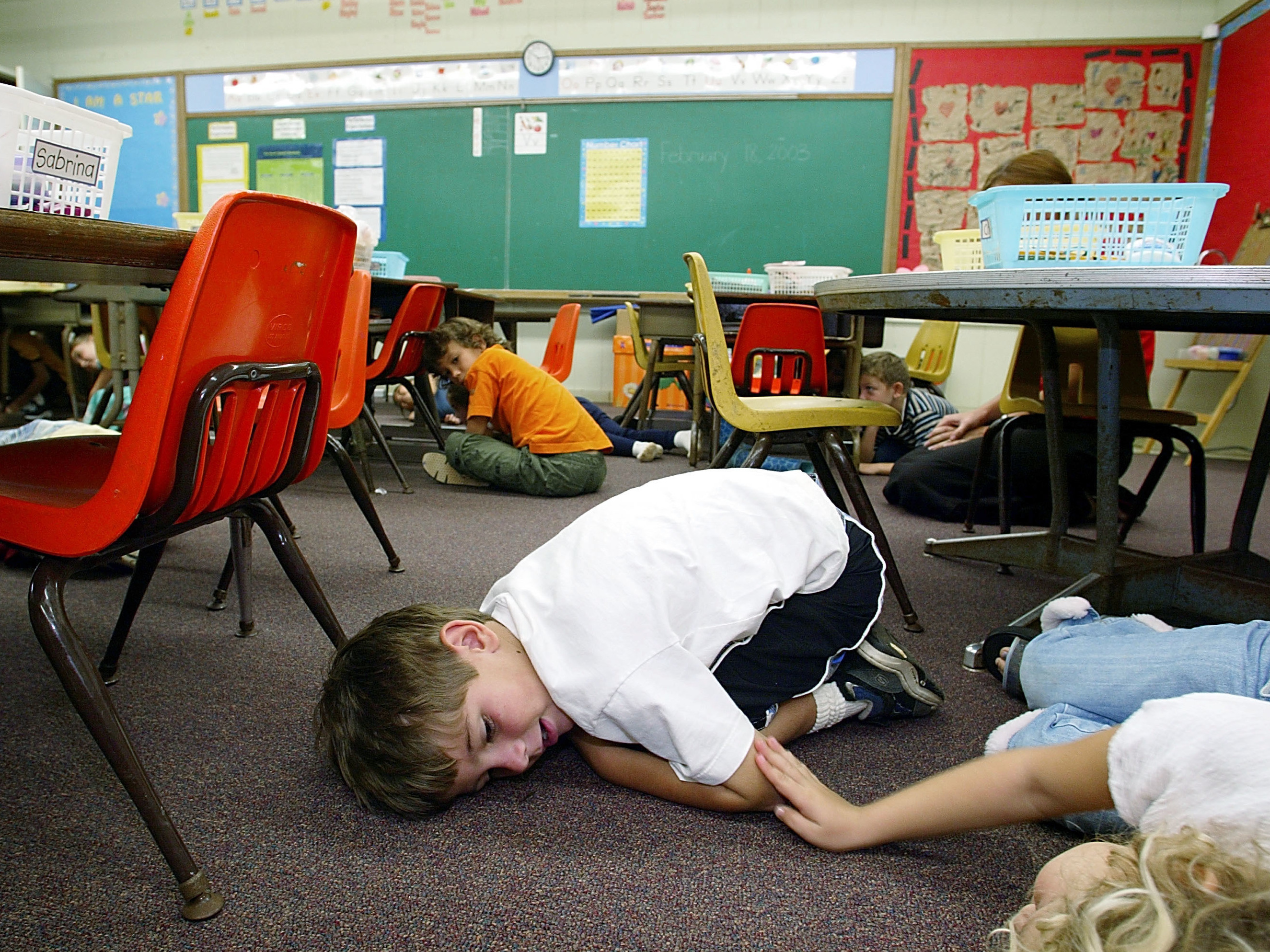 Kindergarten students in Oahu, Hawaii, lie on the floor during a lockdown drill in 2003. (Getty Images)