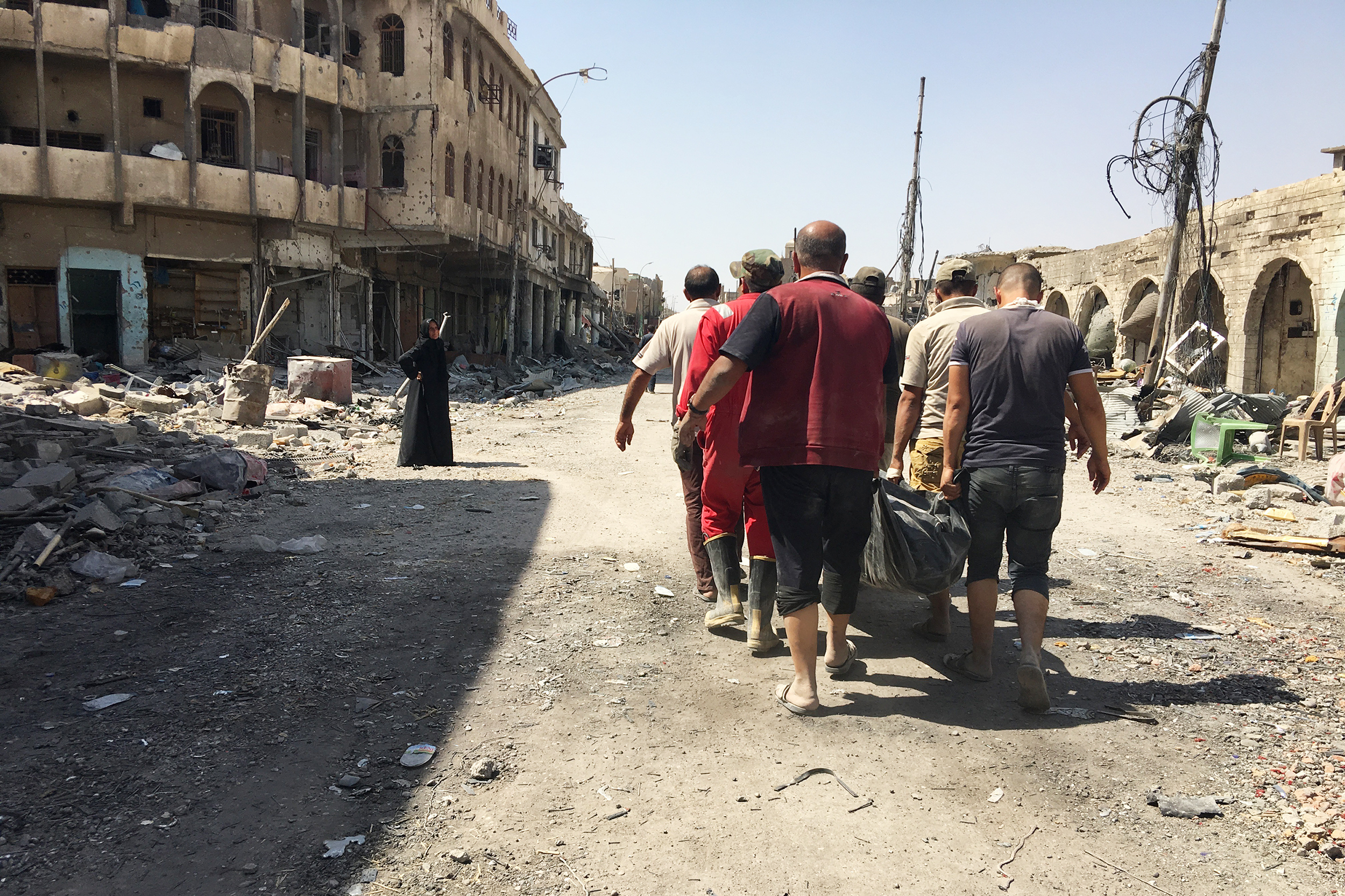 Civil defense workers carrying the body of a civilian retrieved from the rubble of a house destroyed in airstrike. They've collected almost 1,500 bodies so far in west Mosul – many of them women and children – and are still finding casualties. (NPR)