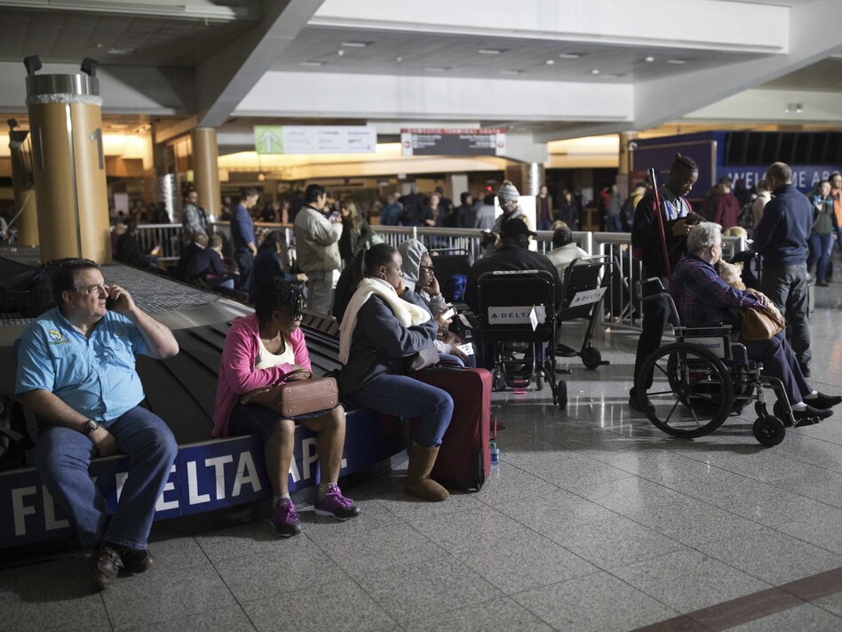 Passengers wait after the lights went out at Hartfield-Jackson Atlanta International Airport on Sunday. Many travelers were stuck in grounded planes for hours. (Branden Camp/AP)