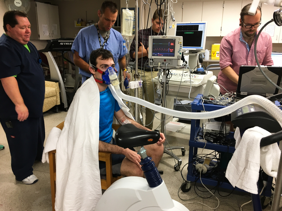 Volunteer Greg Ruegsegger is outfitted with monitors, a catheter threaded into a vein and a mask to capture his breath in an experiment run by Joyner to measure human performance. (Richard Harris/NPR)