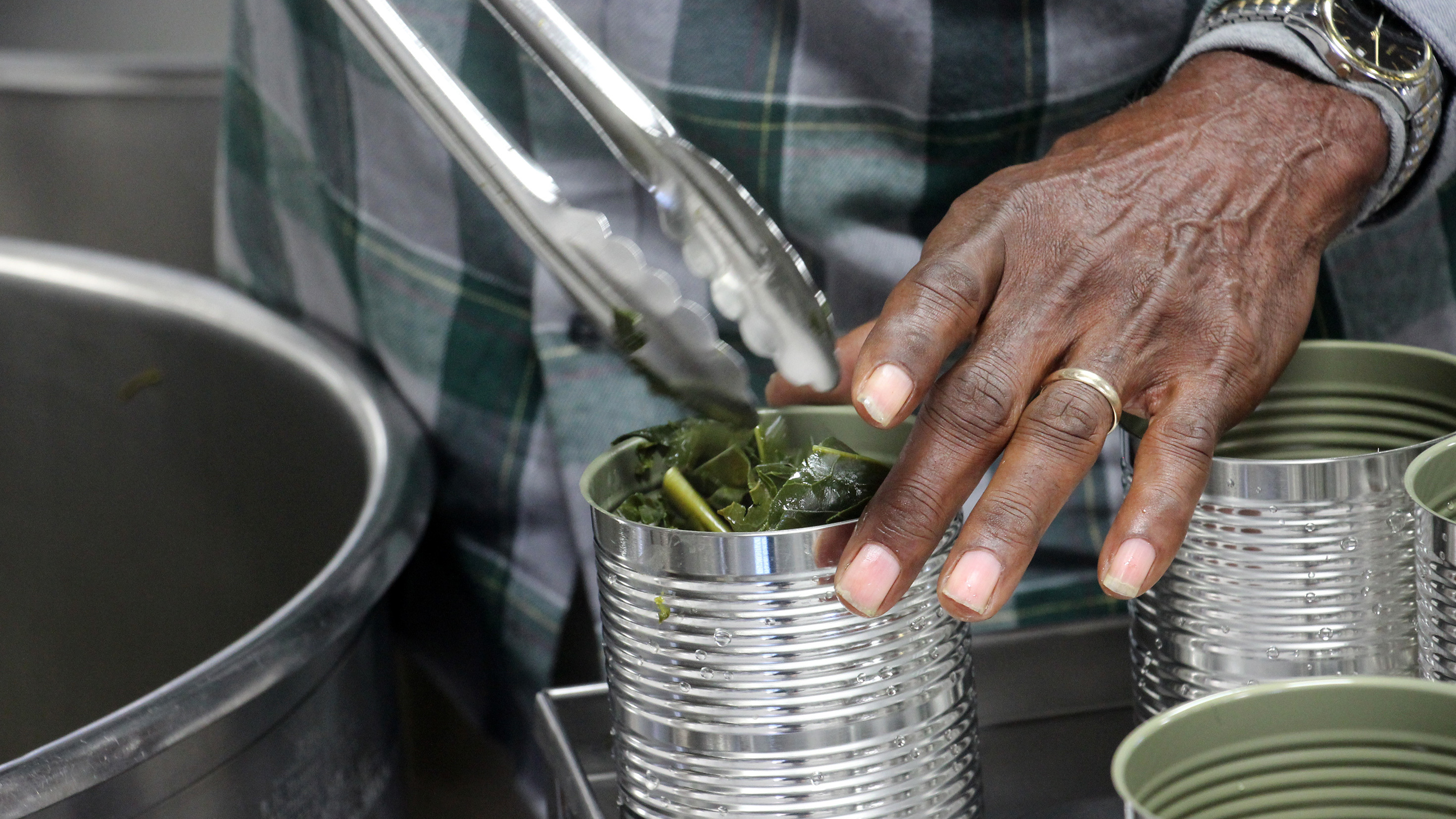 Roy Miller fills cans with cooked collard greens.