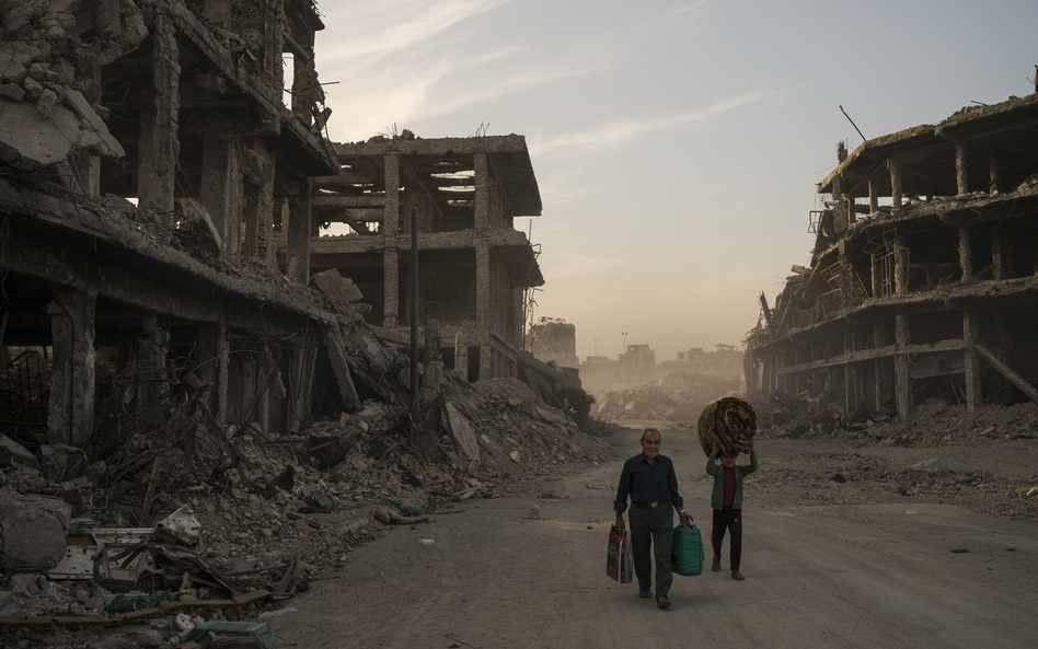 Two civilians carry belongings they collected from their damaged house in the Old City of Mosul, Iraq. The Islamic State controlled the northern Iraqi city for three years before being driven out last year. ISIS no longer controls any cities, but small groups of fighters remain in Iraq and Syria, and are still considered a threat. (Felipe Dana/AP)