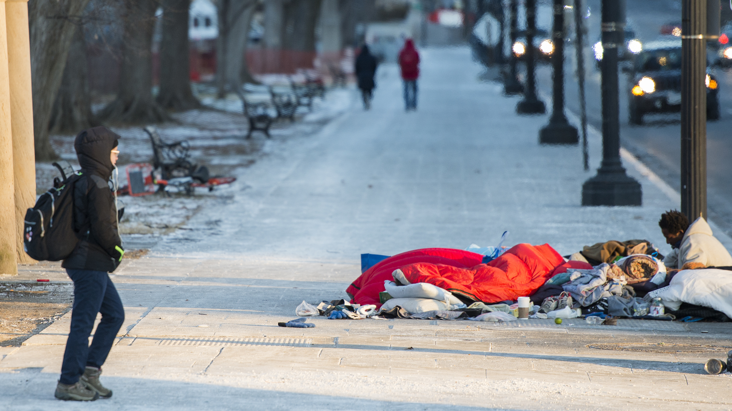 A man rests on top of a subway vent grate as a tourist walks past in Washington, D.C., on Jan. 5. (AFP/Getty Images)