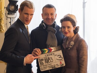 Peter Morgan (center) poses with Matt Smith, who plays Prince Philip, and Claire Foy, who plays Queen Elizabeth II, on the set of The Crown. Morgan also wrote the screenplays for The Queen and Frost/Nixon. (Alex Bailey/Netflix)