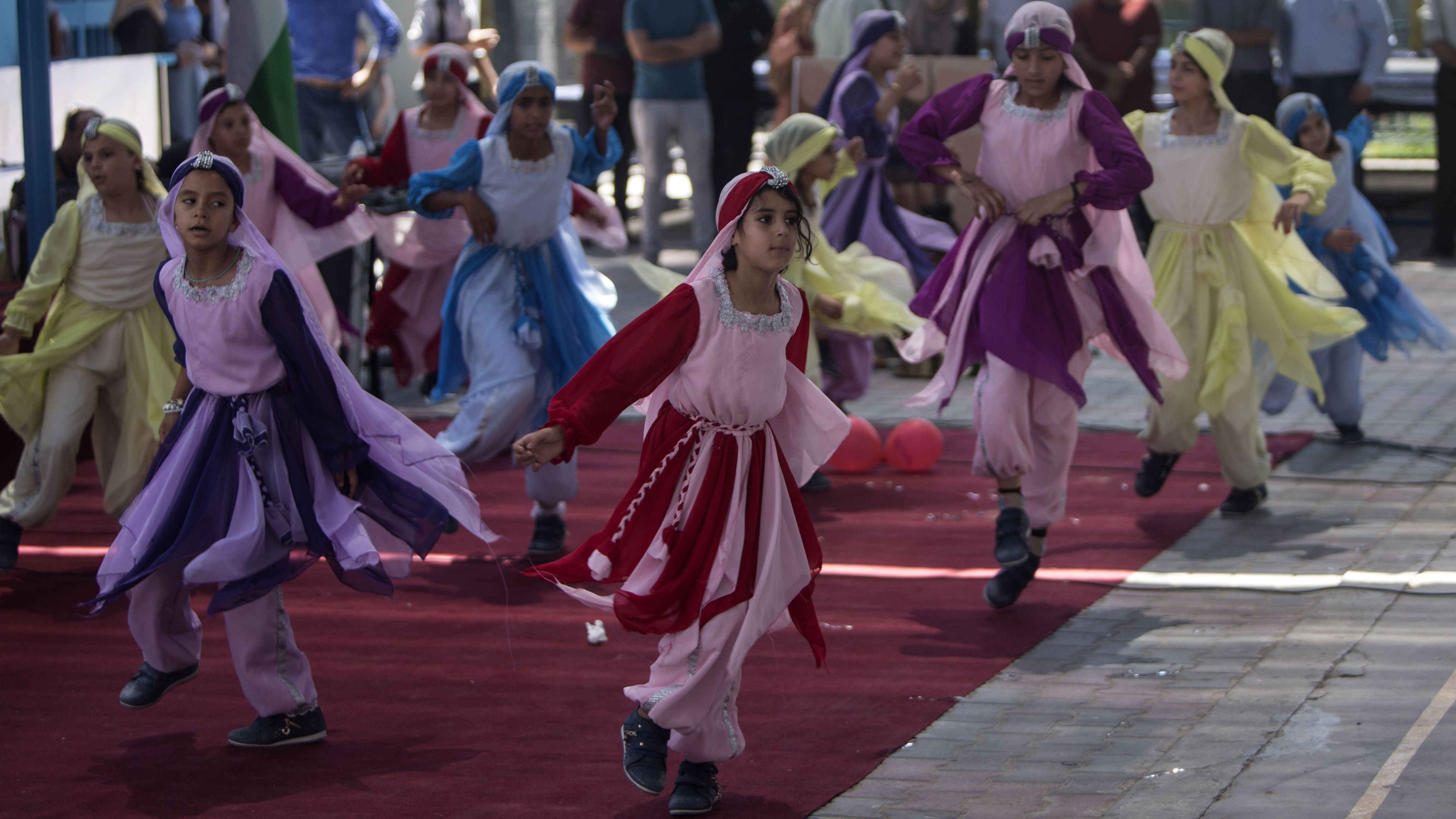 The U.S. says it's sending money to sustain schools and health services for Palestinian refugee. In this 2016 photo, schoolgirls dance at a summer camp organized at a U.N. Relief and Works Agency school in Gaza City. (AFP/Getty Images)