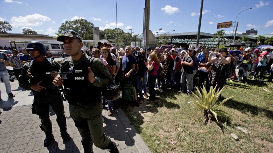 Venezuelan Bolivarian National Guards officers control shoppers as they line up outside a supermarket to buy food at discounted prices in Caracas on Jan. 6. (Fernando Llano/AP)