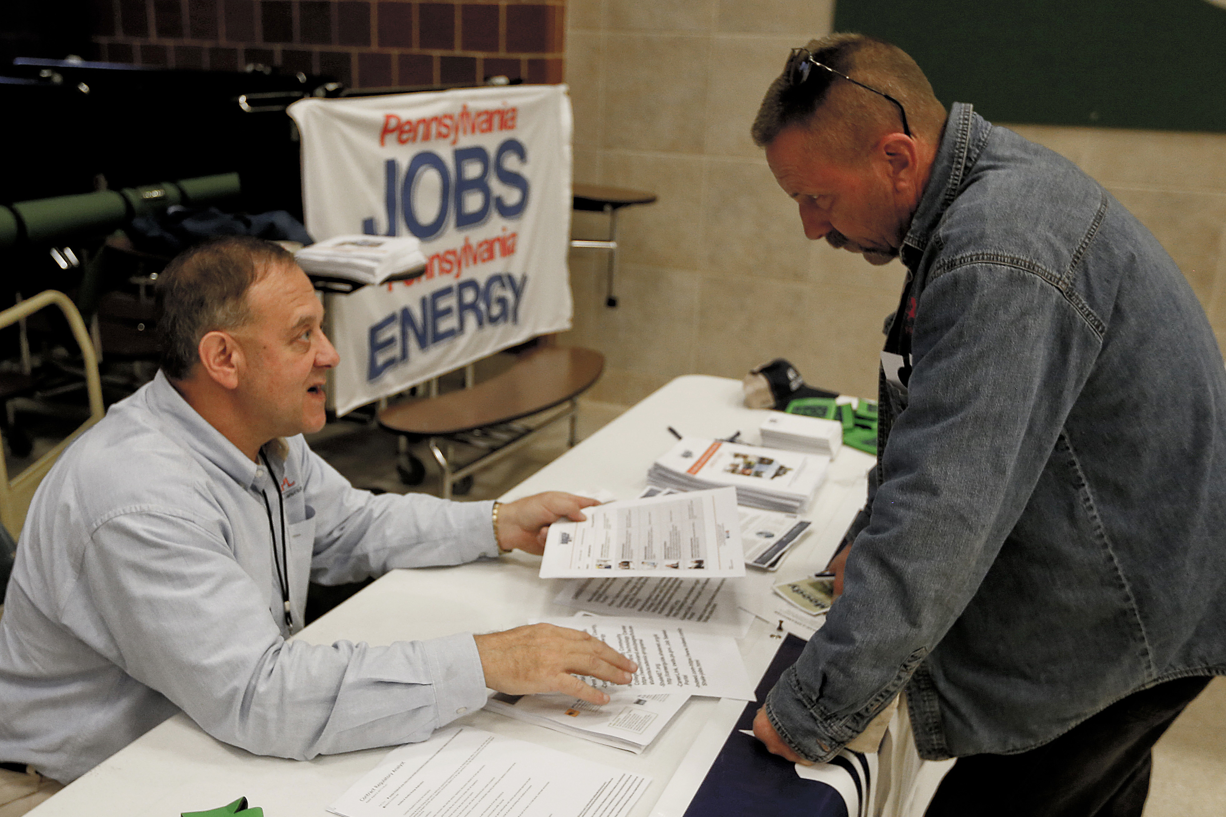 In this Nov. 2, 2017, photo, a recruiter in the shale gas industry, left, speaks with an attendee of a job fair in Cheswick, Pa.