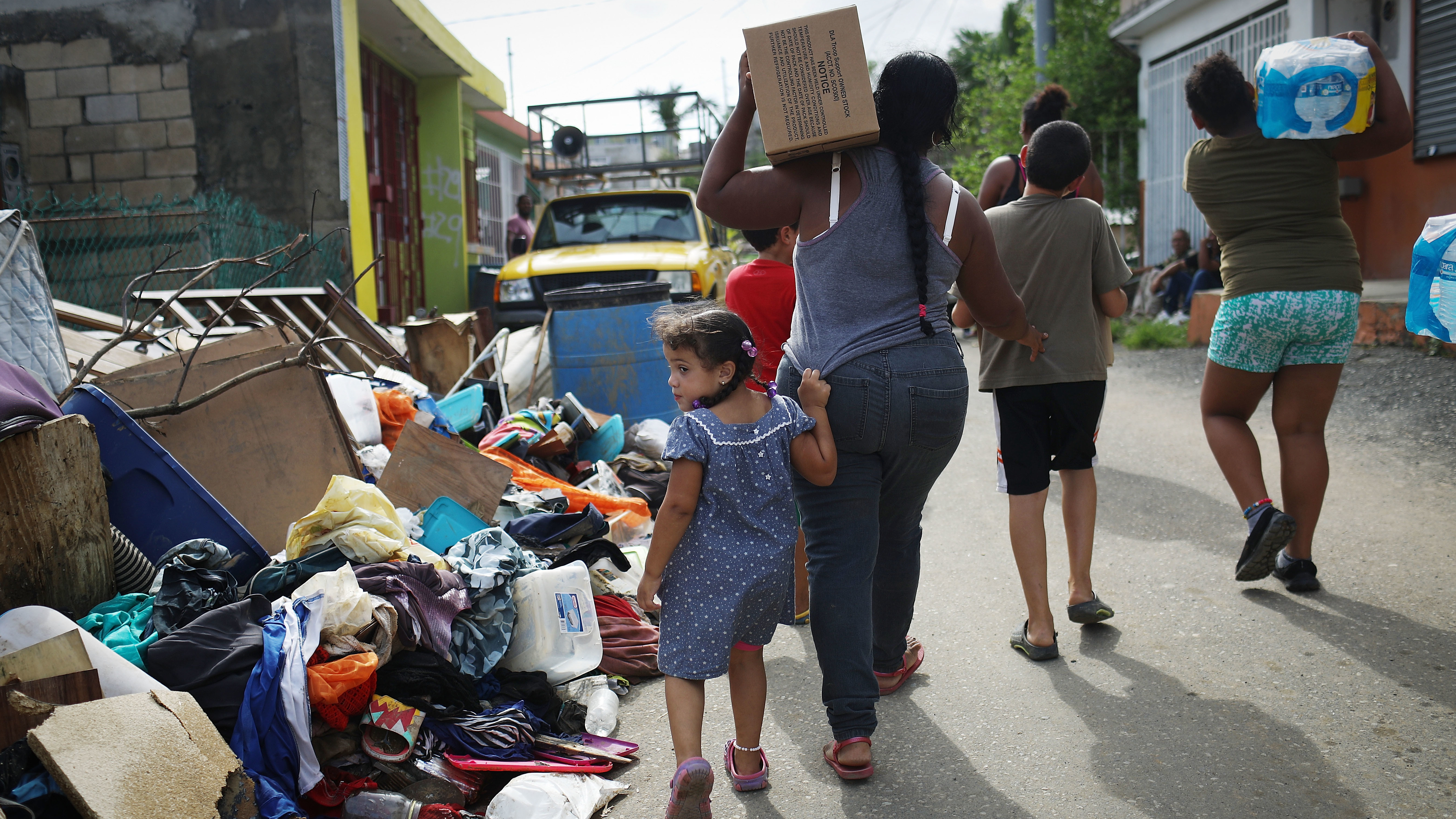 Residents of San Isidro, Puerto Rico carry food and water provided by FEMA to a neighborhood without electricity or running water last October.