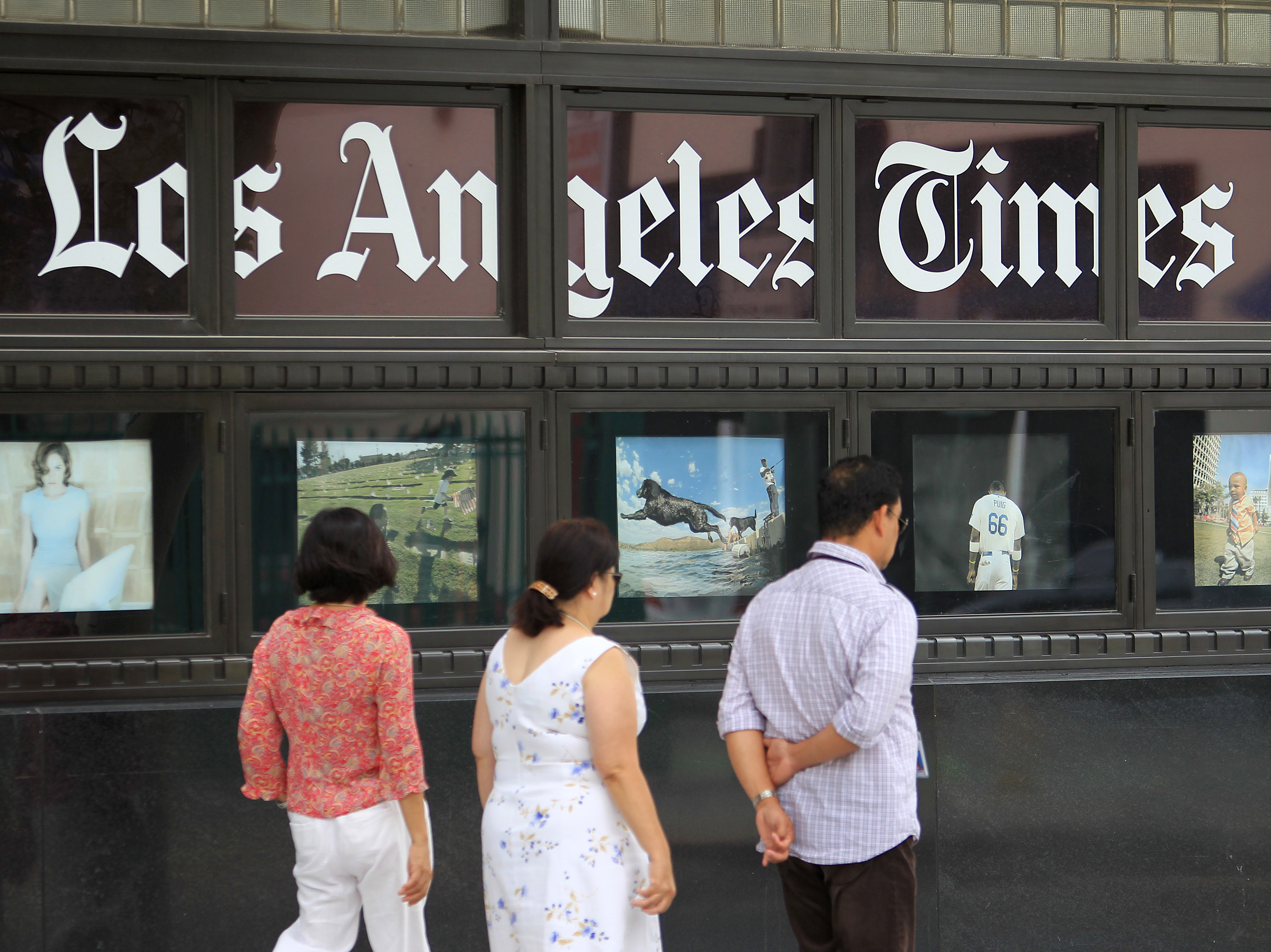 Pedestrians pass photos displayed on the <em>Los Angeles Times</em> building in 2013. Business Editor Kimi Yoshino returned to the newsroom Thursday. (Getty Images)