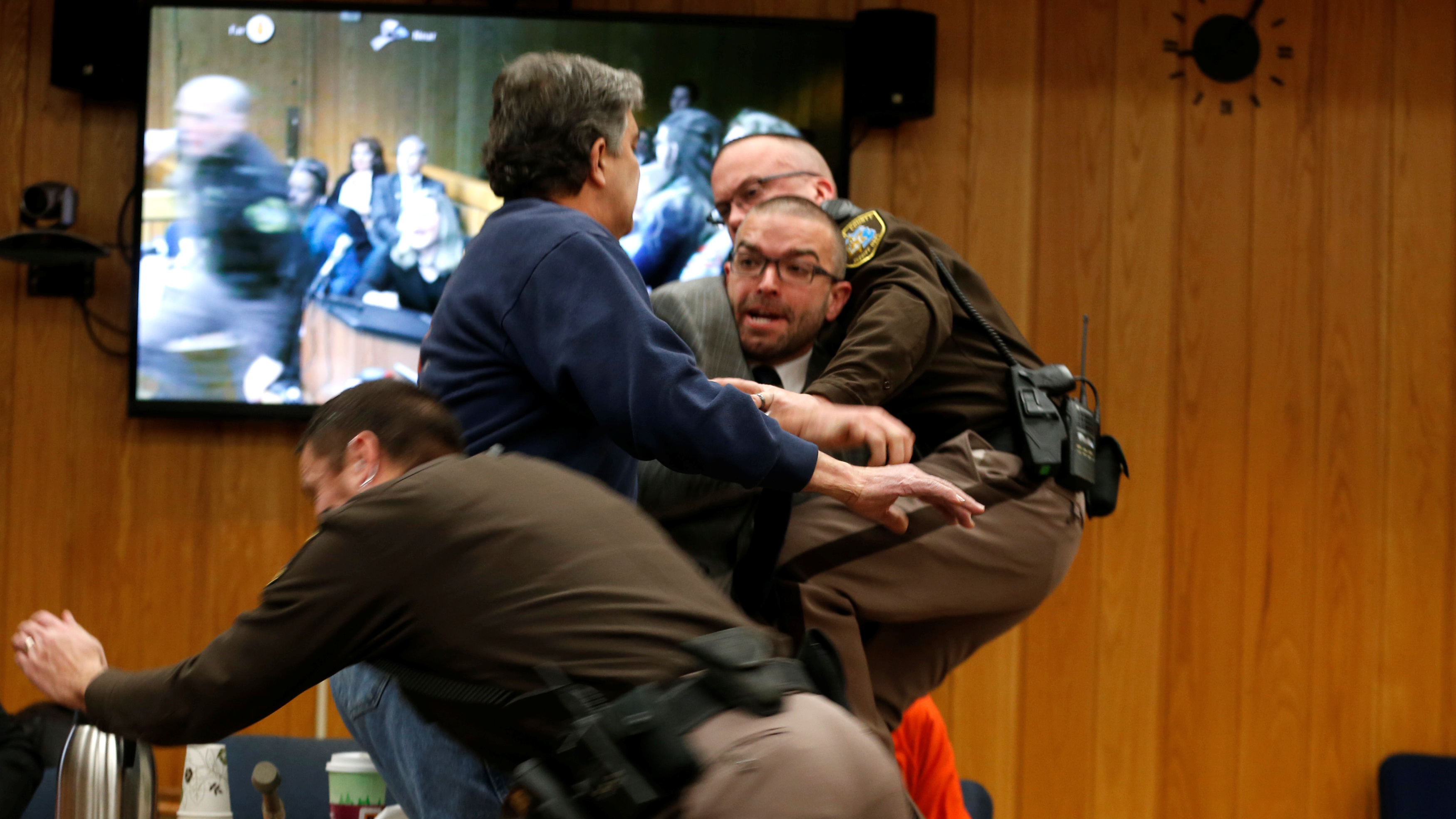 Randall Margraves (in blue sweatshirt) lunges at Larry Nassar (in orange) during Nassar
