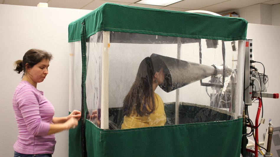 Undergraduate Shira Rubin gamely demonstrates the Gesundheit machine, which collects samples of virus from the breath that sick students exhale. Rubin helps <a href="https://gotflu.umd.edu/people.html#syoussefi">Dr. Somayeh Youssefi</a> (left) set up the machine before patients use it. (Selena Simmons-Duffin/WAMU)