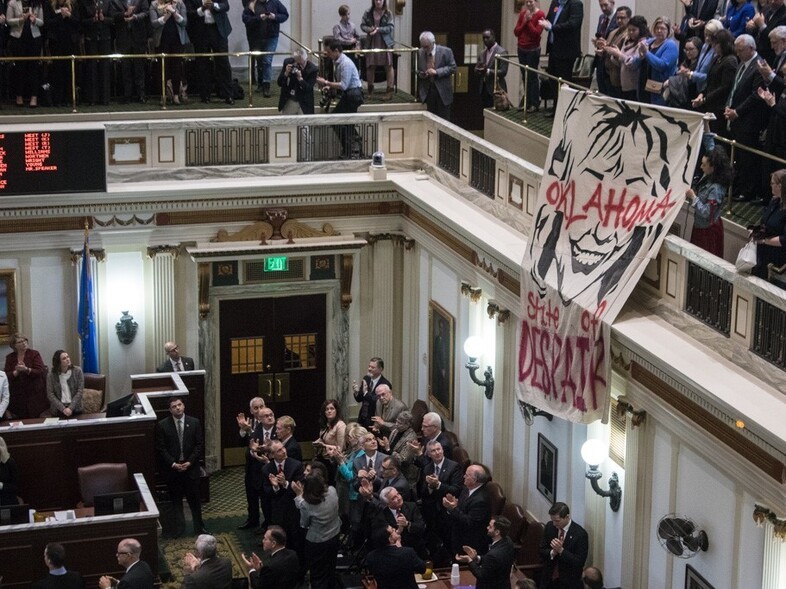 Protesters unfurl a caricature of Oklahoma Gov. Mary Fallin at the end of her State of the State address on Monday. (Emily Wendler/StateImpact Oklahoma)