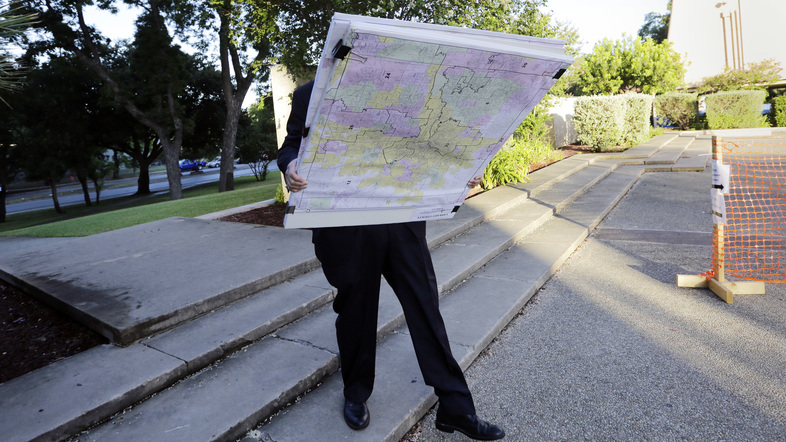 A man with a set of maps heads to a federal courthouse in San Antonio last year for a redistricting trial. Texas is one of three states with cases in redistricting before the Supreme Court. (Eric Gay/AP)