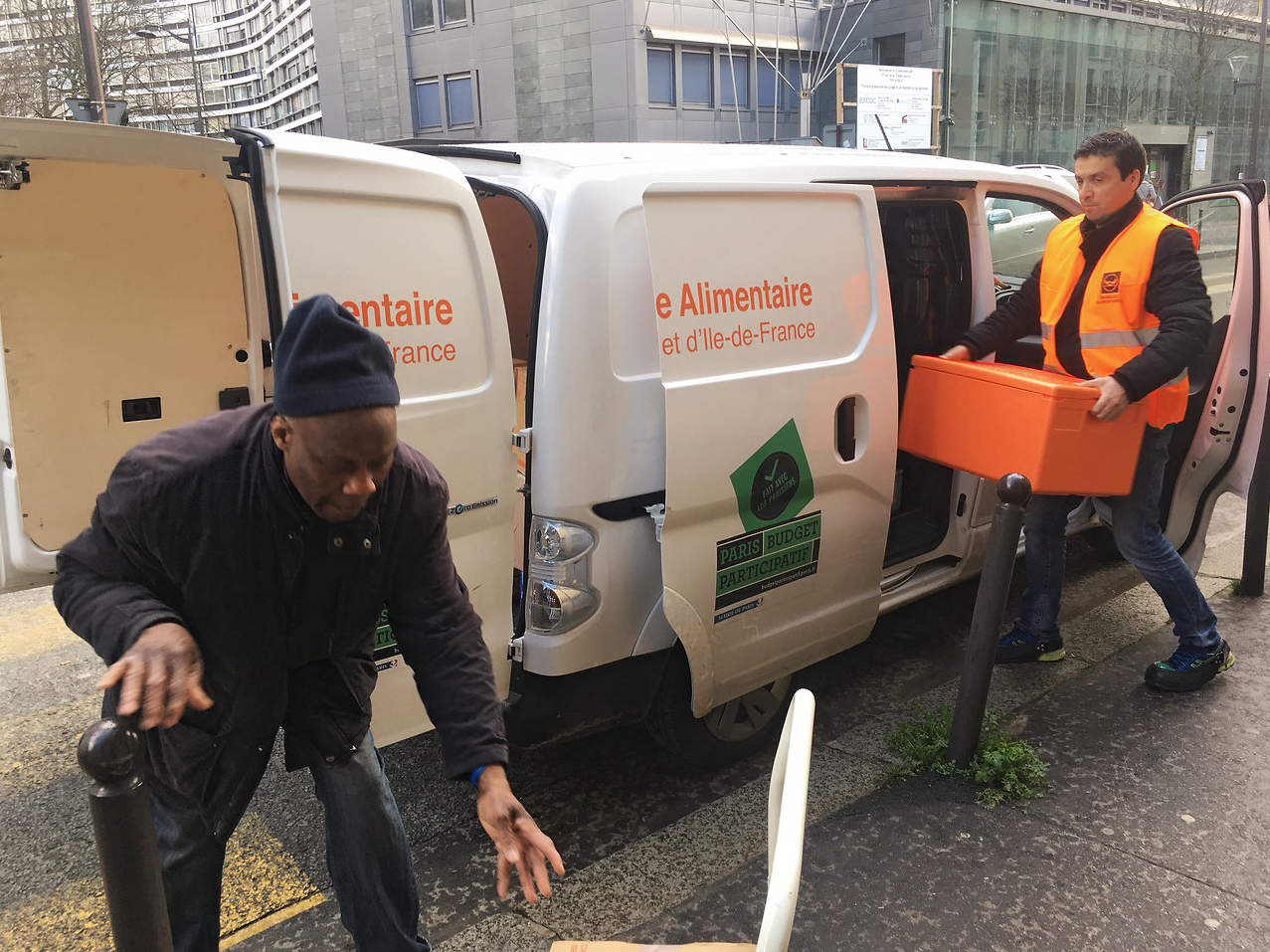 Ahmed &quot;Doudou&quot; Djerbrani, in the orange vest, delivers the food French supermarkets must donate to food banks by law. (NPR)
