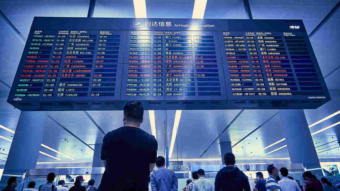 People waiting at an airport arrivals and departure board
