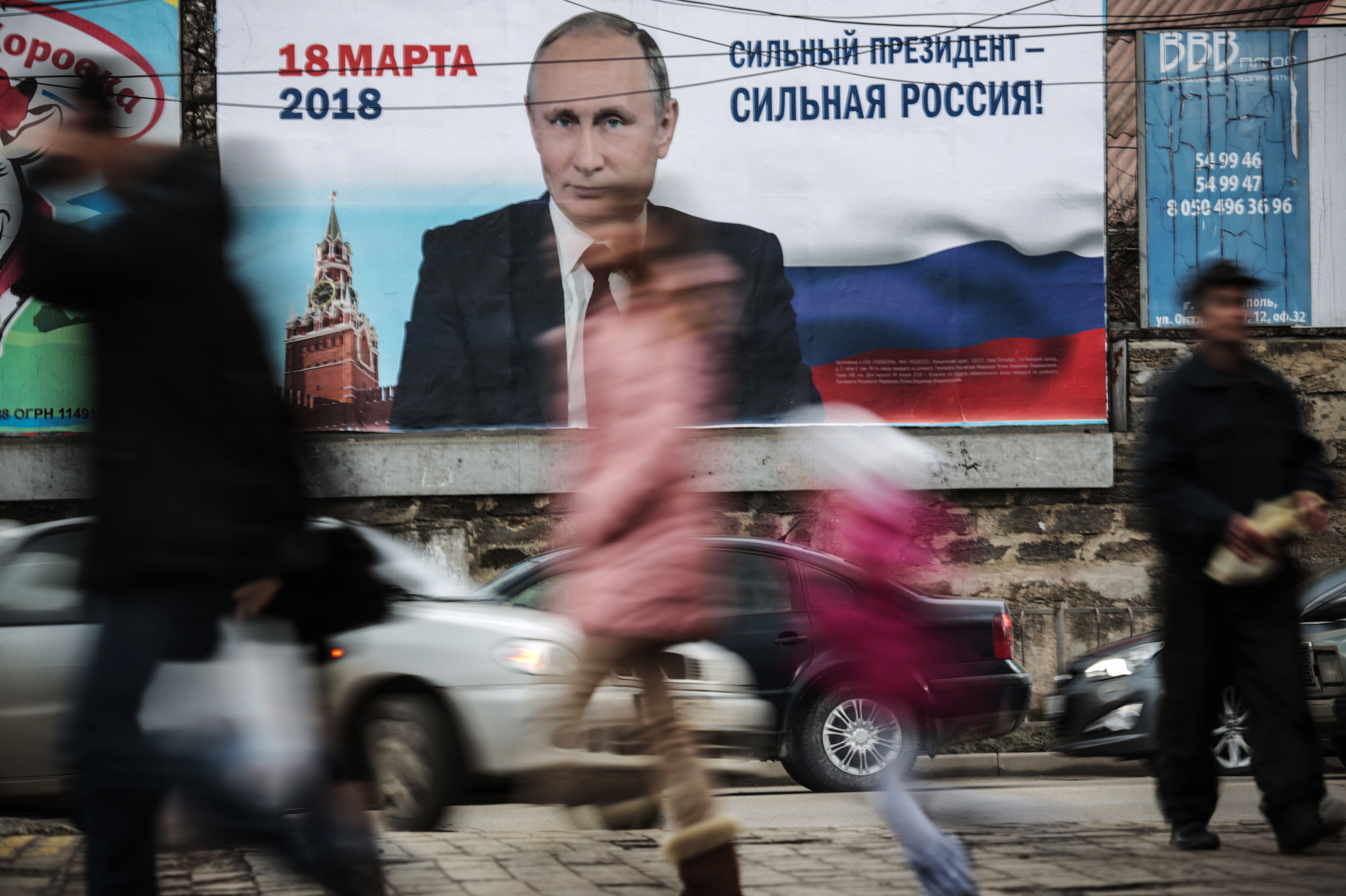 Pedestrians pass by a billboard with an image of Russia's President Vladimir Putin and lettering &quot;Strong president - Strong Russia!&quot; in Simferopol, Crimea in January. (AFP/Getty Images)