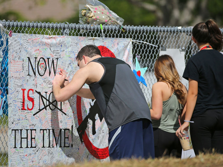 A man signs a banner against guns as mourners pay tribute at a memorial on Feb. 25 for the victims of the shooting at Marjory Stoneman Douglas High School. (TNS via Getty Images)
