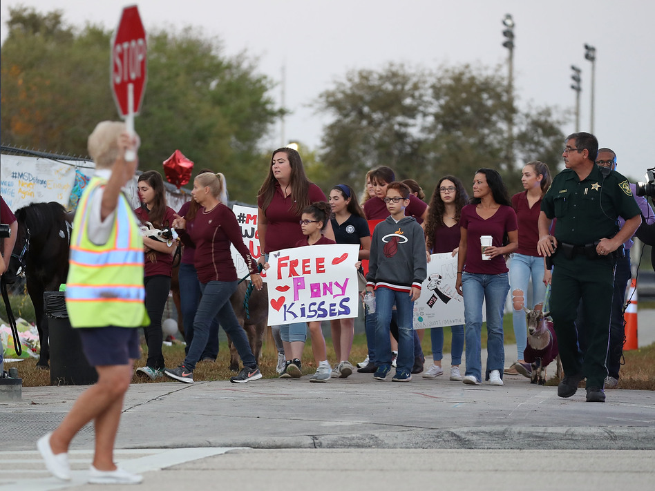 Onlookers offer support Wednesday at a crosswalk as students arrive for their first classes at Marjory Stoneman Douglas High School since a massacre there two weeks ago killed 17 people. (Joe Raedle/Getty Images)