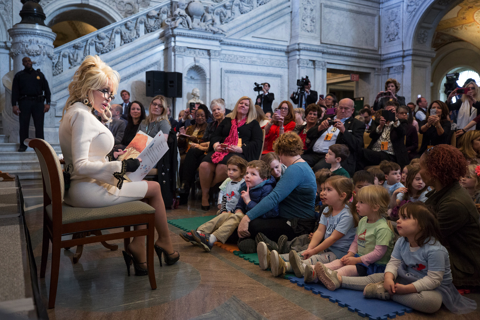 Dolly Parton reads <em>Coat of Many Colors</em>, a children's book based on one of her signature songs, to a group of children at the Great Hall of the Library of Congress in Washington, D.C., on Tuesday. (Library of Congress)