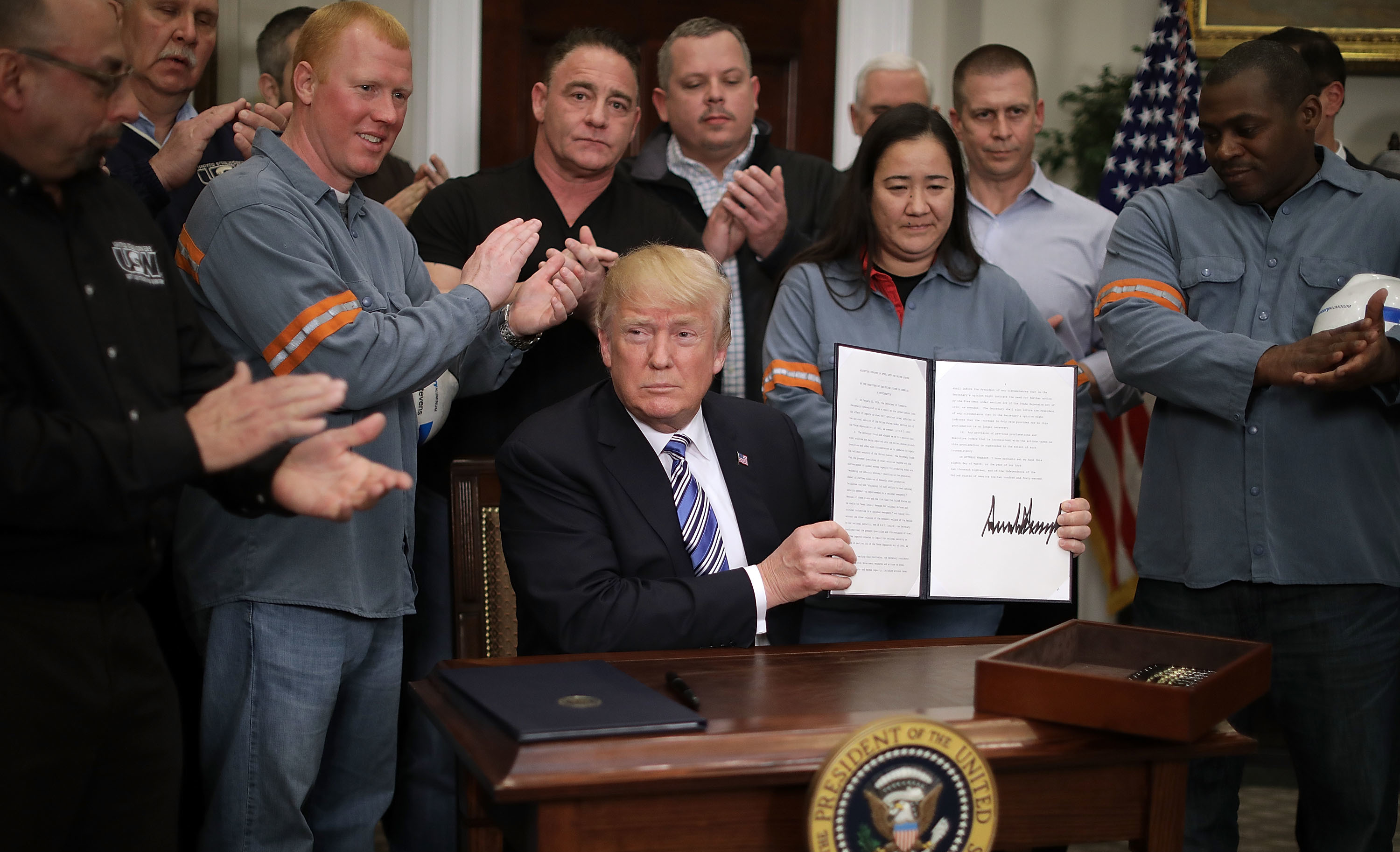 Surrounded by steel and aluminum workers, President Trump holds up the order on steel imports that he signed in Roosevelt Room at the White House on Thursday. (Getty Images)