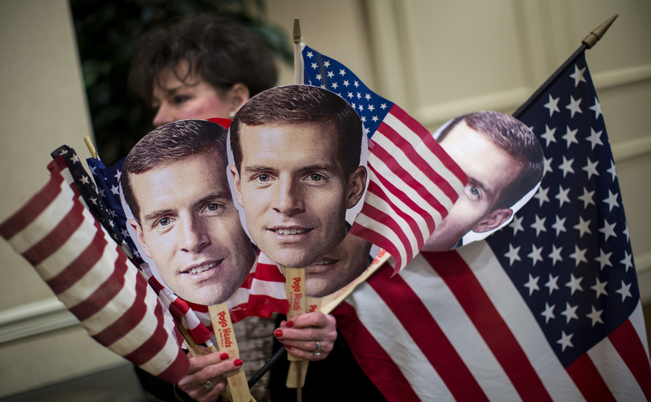 A supporter carries flags and photos of Conor Lamb at an election night event on Tuesday for the Democrat, who has apparently won the congressional seat in Pennsylvania's 18th District.