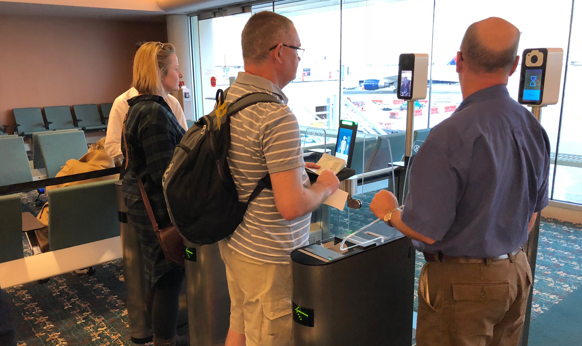 Passengers use facial recognition scanners before boarding a British Airways flight in Orlando, Fla. (NPR)