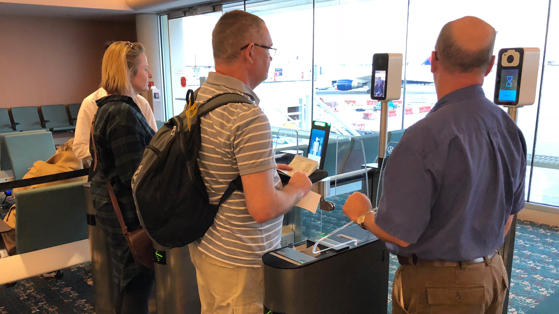 Passengers use facial recognition scanners before boarding a British Airways flight in Orlando, Fla.