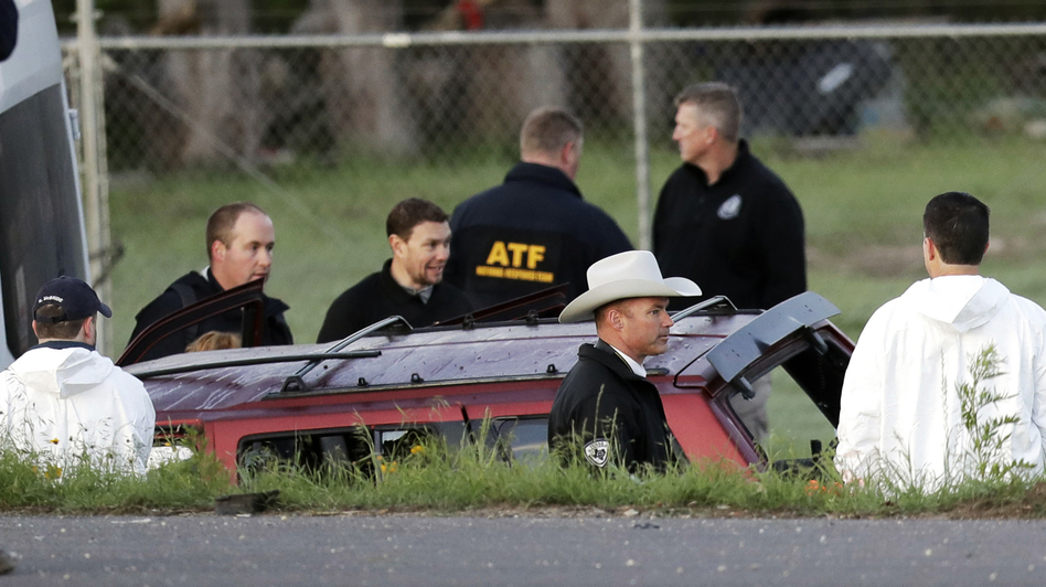 Officials investigate the scene where suspect Mark Anthony Conditt died in an explosion early Wednesday. His red vehicle was trapped between two white vans in Round Rock, Texas. (Eric Gay/AP)