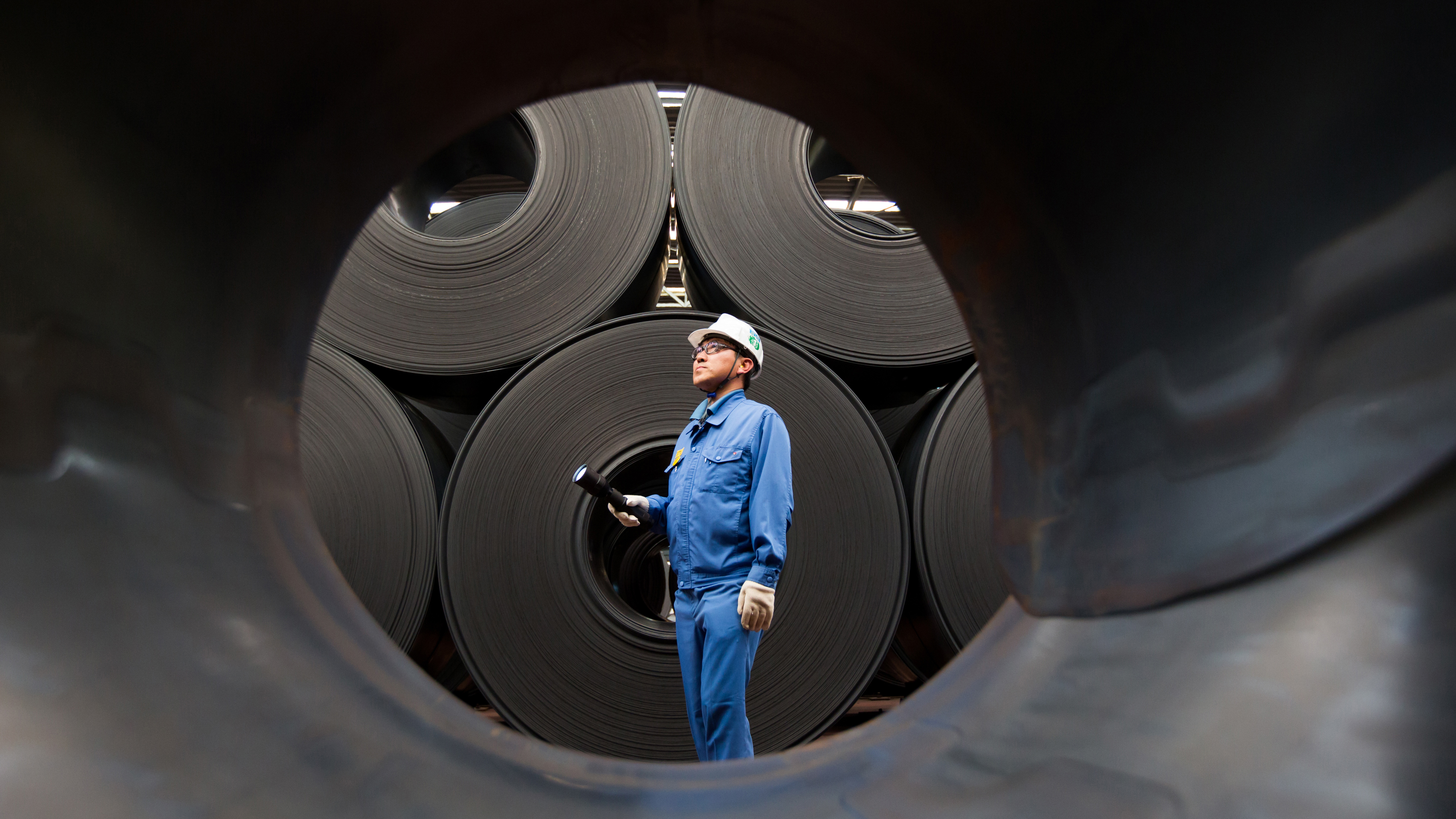 A quality control engineer examines hot-rolled coils of steel being stored in 2015 at South Korean manufacturer POSCO's facility. (Worldsteel via Getty Images)
