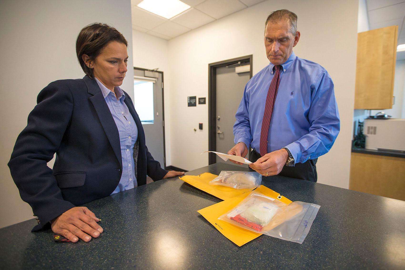 Arlington, Mass., Police Chief Fred Ryan (right) and Inspector Gina Bassett review toxicology reports on cocaine evidence looking for the possibility of fentanyl. (Jesse Costa/WBUR)