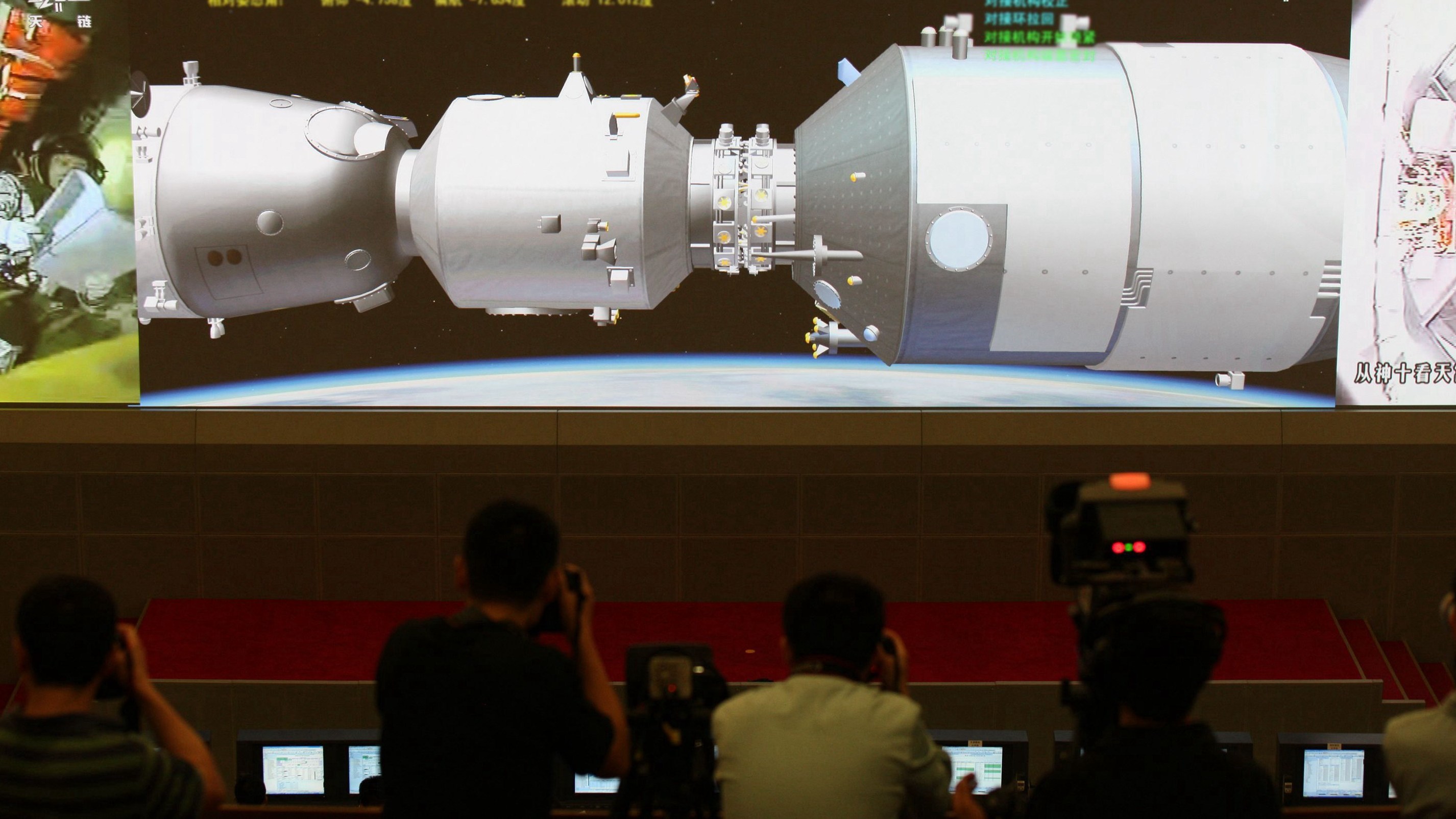 Scientists look at the screen showing the Shenzhou X manned spacecraft docking with the orbiting Tiangong-1 space module at Beijing Aerospace Control Center on June 13, 2013, in Beijing.