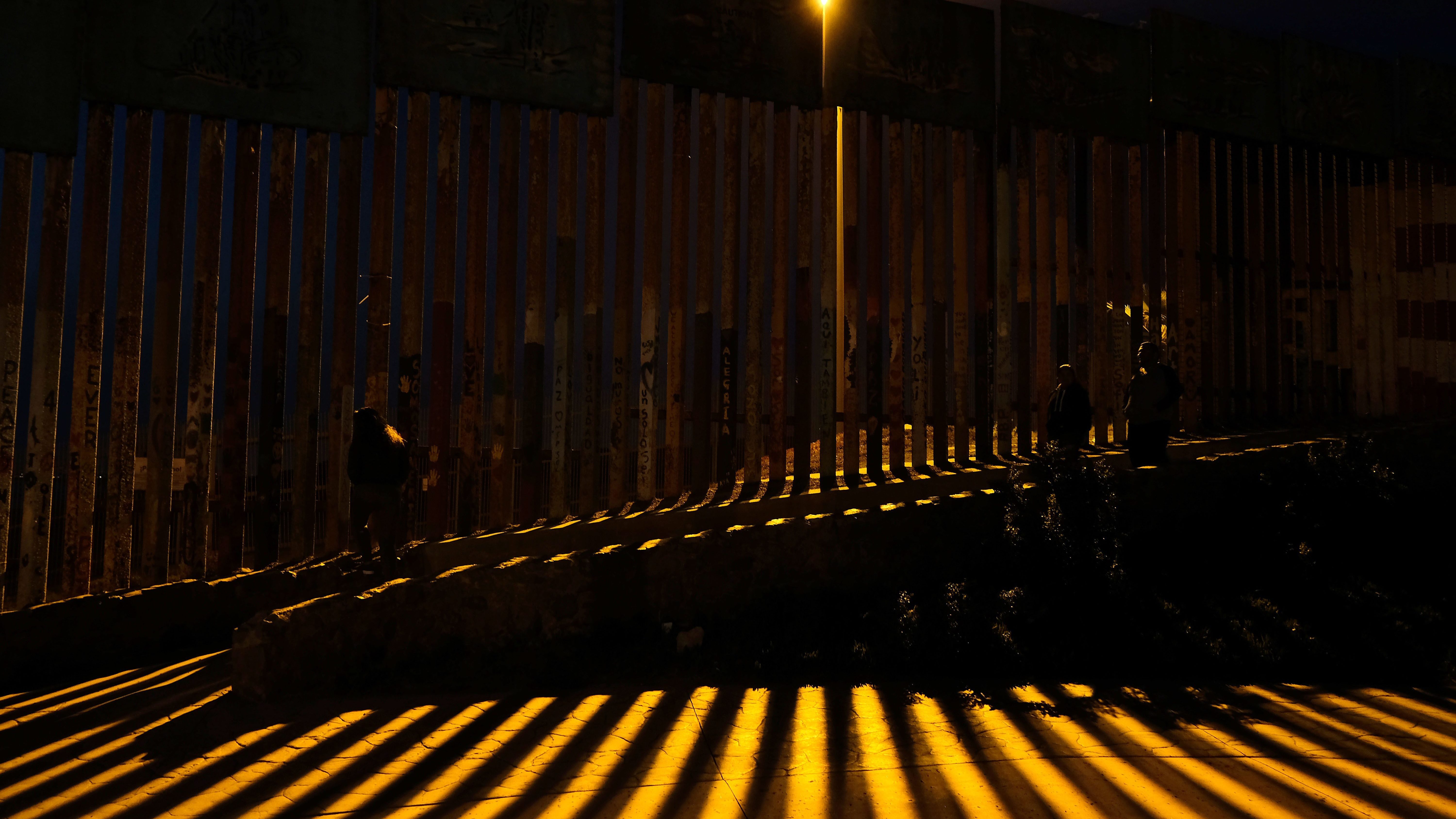 People walk near the fence of the Mexico-U.S. at Playas de Tijuana in northwestern Mexico. (AFP/Getty Images)