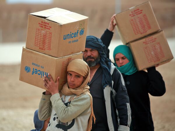 Displaced Syrians, who fled their homes in the city of Deir ez-Zor, carry boxes of United Nations aid at a camp in Syria's northeastern Hassakeh province in February.