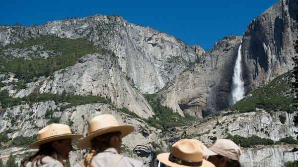 Park rangers meet in front of Yosemite Falls in 2016 in Yosemite National Park, California. Increased fees are expected to boost funding for park maintenance across the country.