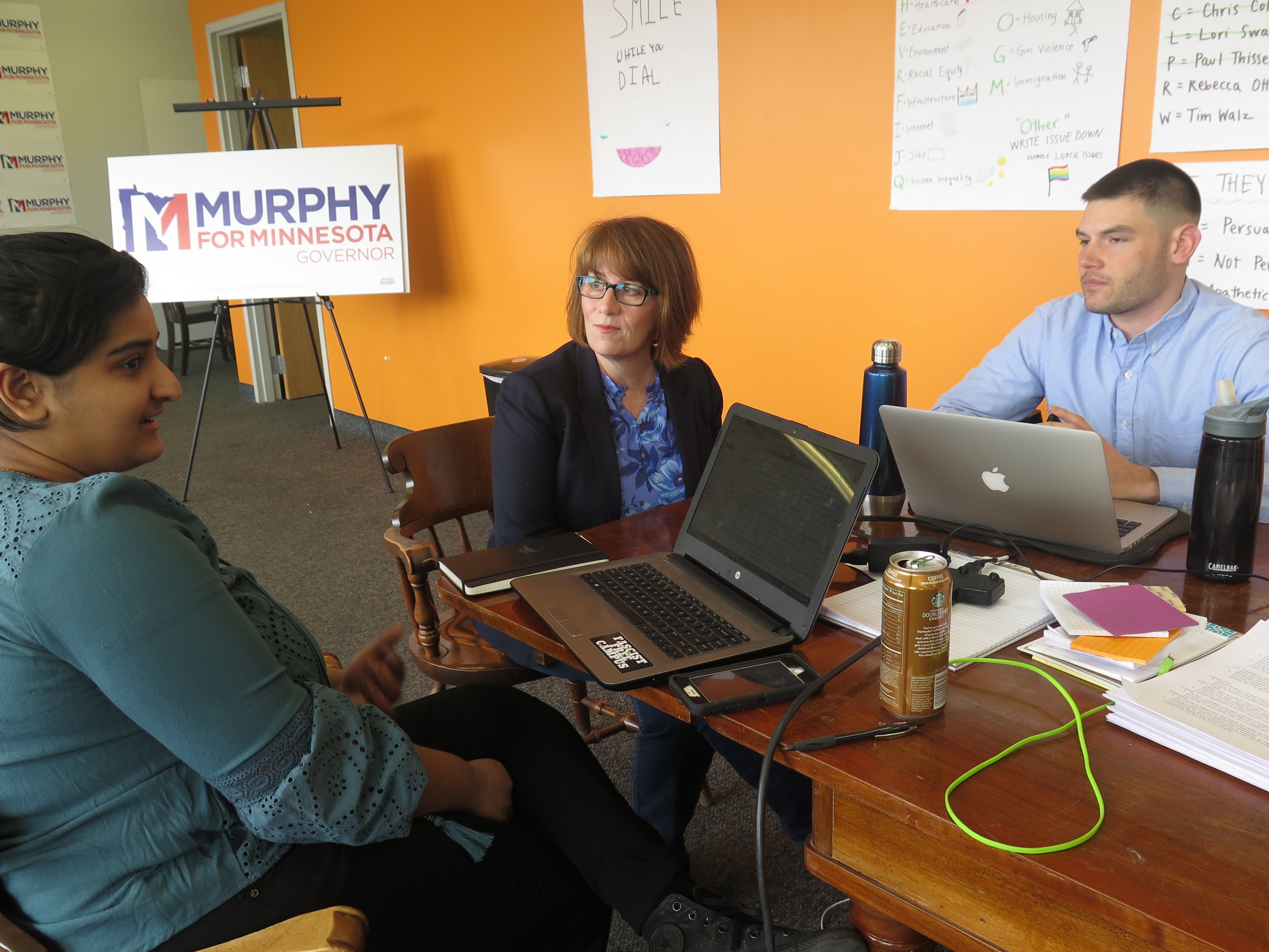 Campaign staff member Aisha Chughtai (left) speaks with Erin Murphy (center), a Democratic candidate for Minnesota governor, at the campaign's St. Paul headquarters as colleague Charles Cox looks on. Chughtai and Cox are members of a newly formed campaign workers union. (MPR News)