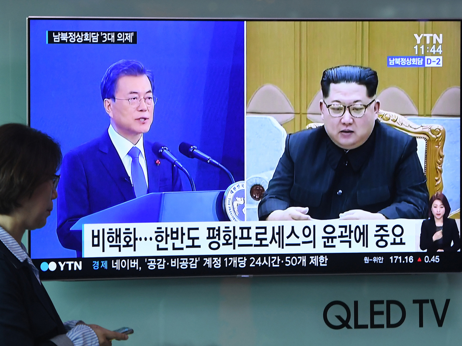 A woman walks past a news screen showing file footage of South Korean President Moon Jae-in and North Korean leader Kim Jong Un at a railway station in Seoul this week. Kim will walk across the Demilitarized Zone on Friday for a historic summit with Moon. (Jung Yeon-Je/AFP/Getty Images)