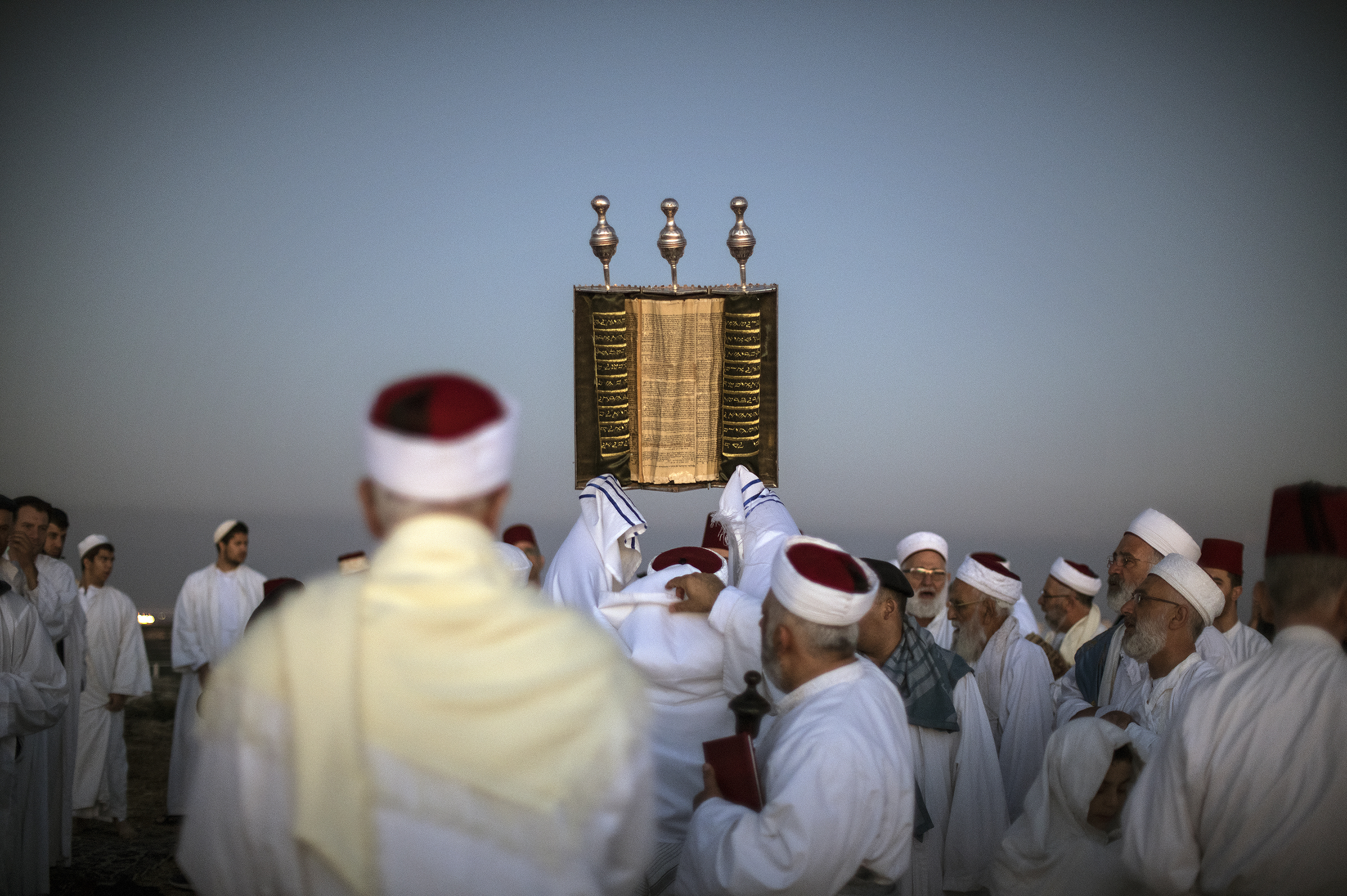 A priest lifts a Samaritan Torah scroll during sunrise prayers on Mount Gerizim in the West Bank. One of the world's oldest and tiniest sects, the Samaritans trace their roots to the ancient Israelites. (Noor Images for NPR)