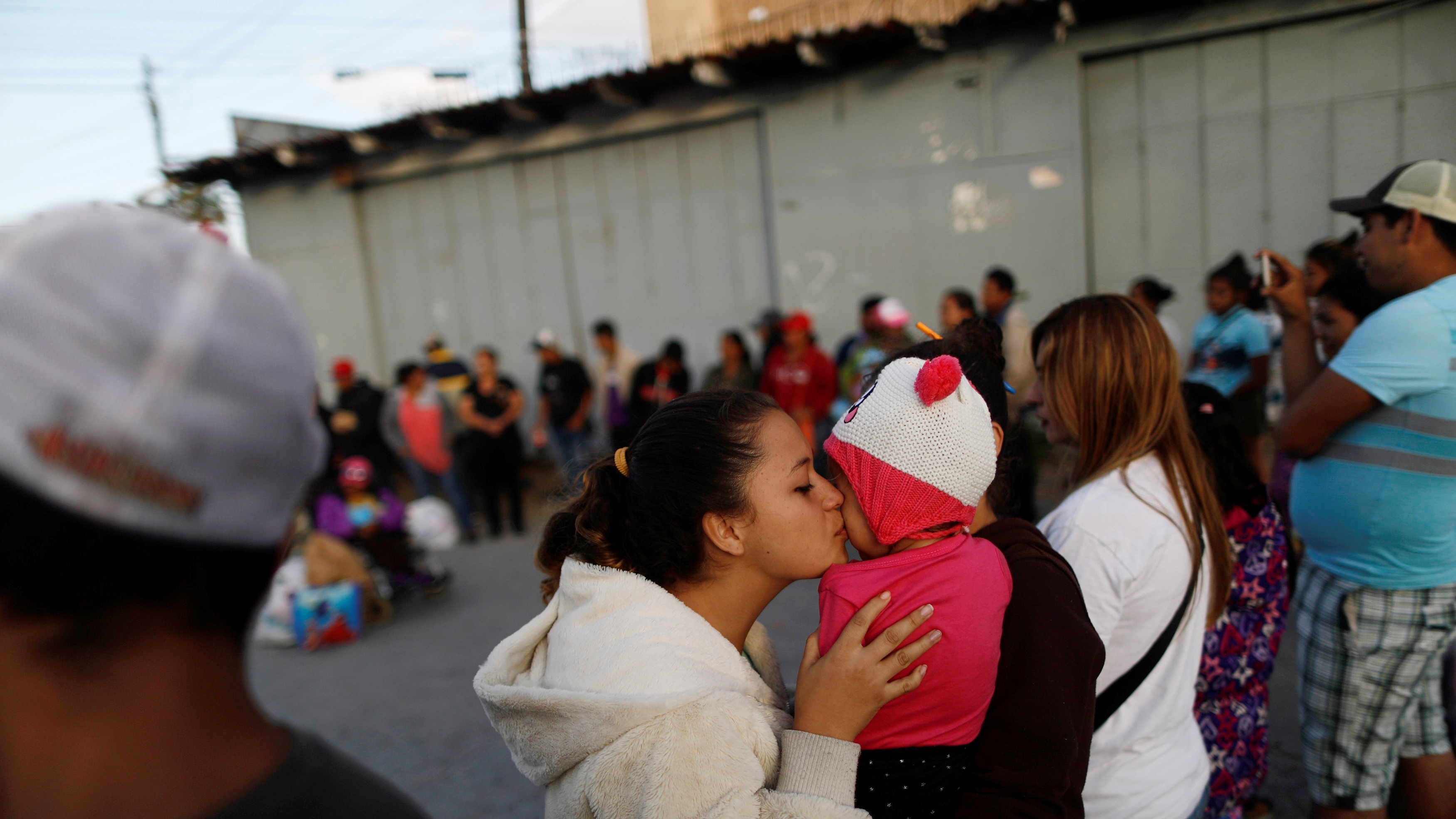 A member of a migrant caravan from Central America kisses a baby as they pray in preparation for an asylum request in the U.S., in Tijuana, Baja California state, Mexico.